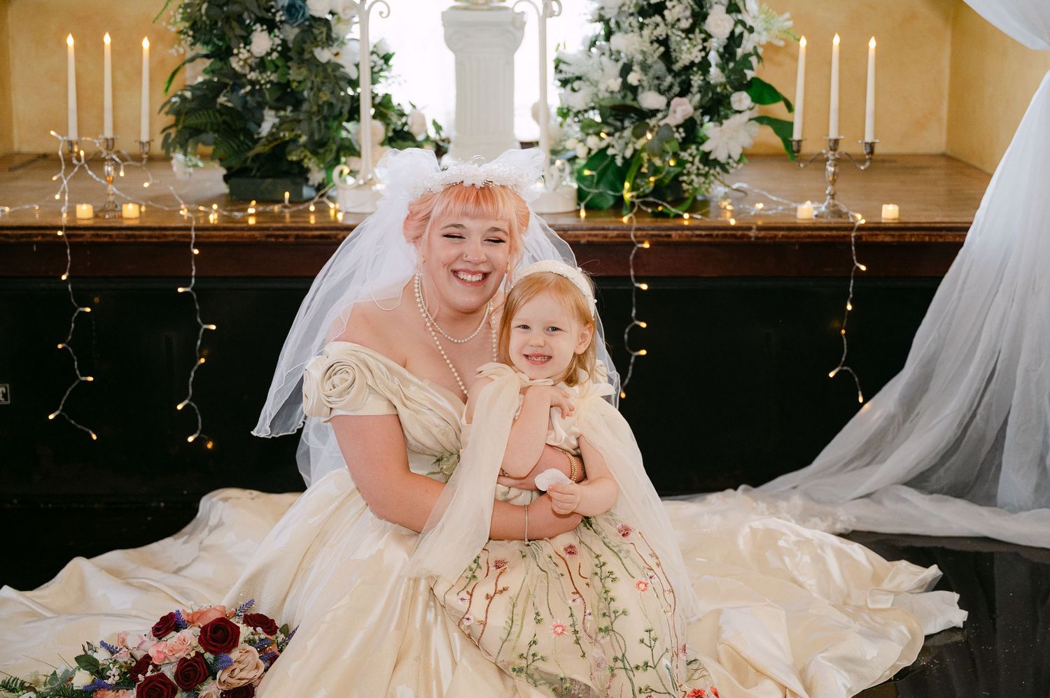 Central MN Wedding Photos | Bride in ivory ball gown with veil hugging young flower girl in floral dress at wedding.