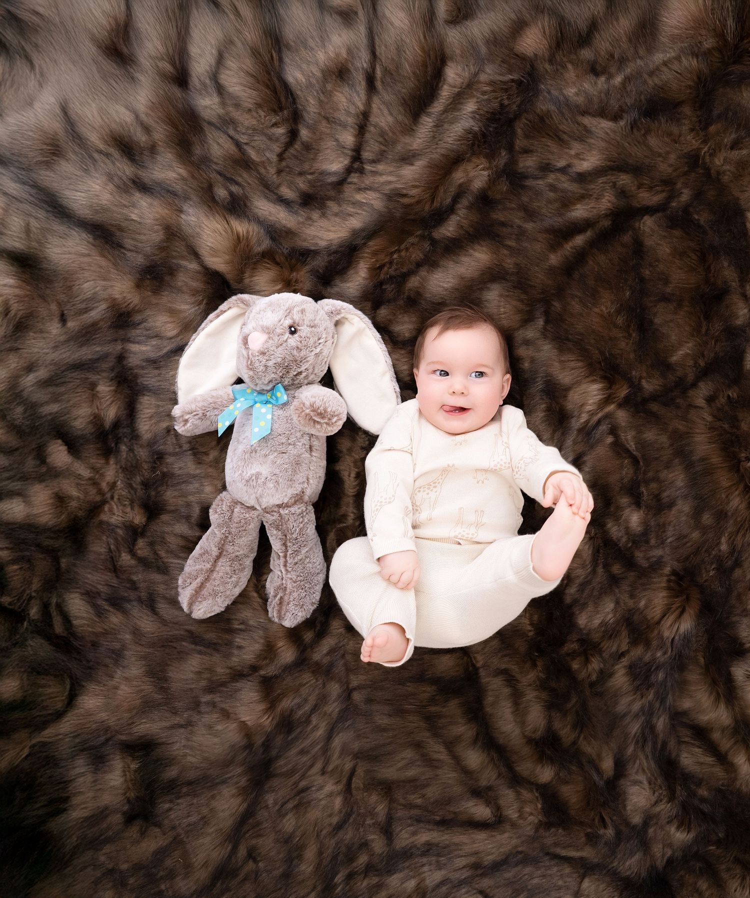 Baby lying on brown fur blanket with stuffed bunny toy during newborn photo session.. Minnesota milestone photographer