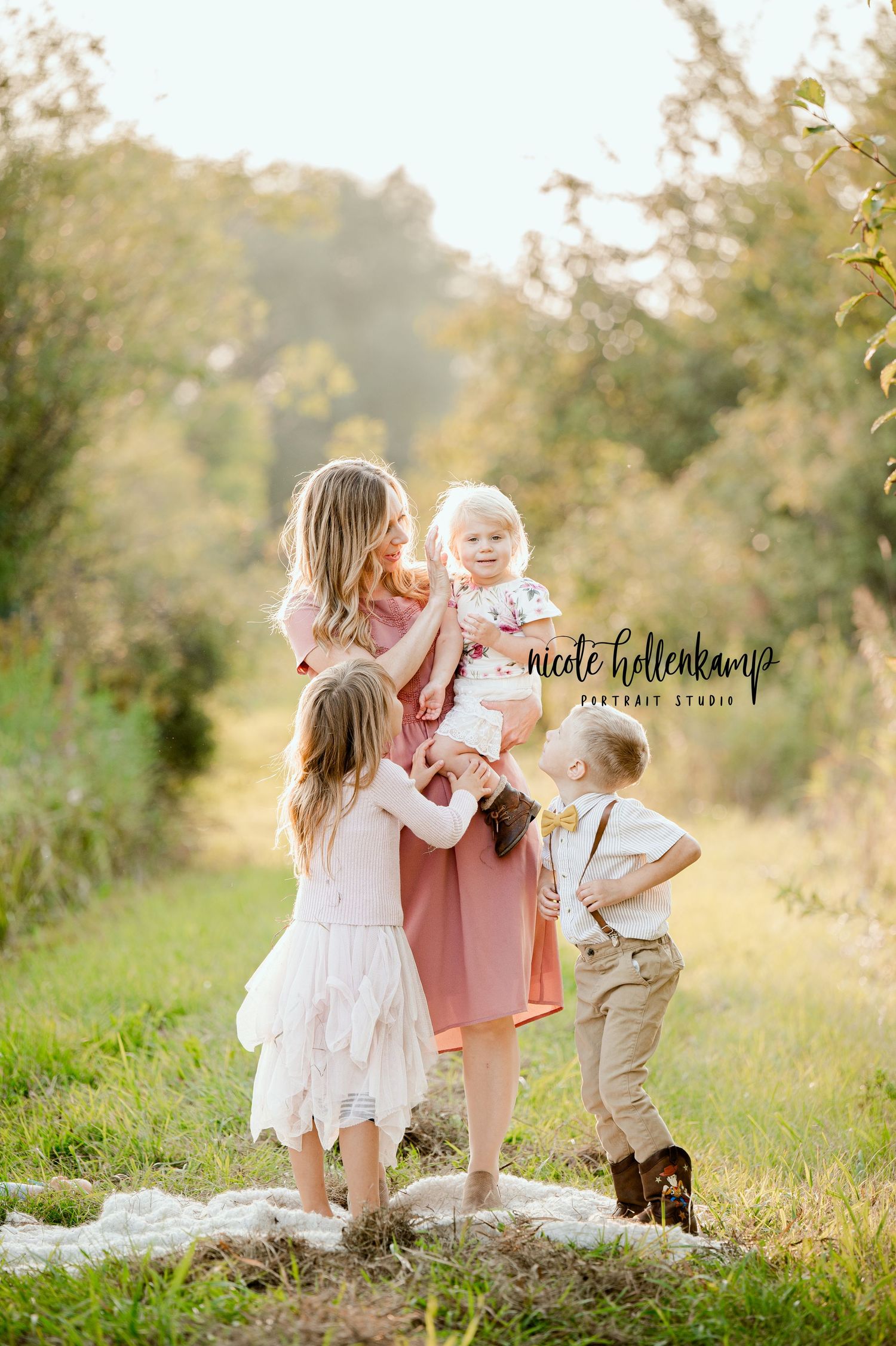 A sunlit outdoor family portrait in a natural pathway surrounded by foliage.