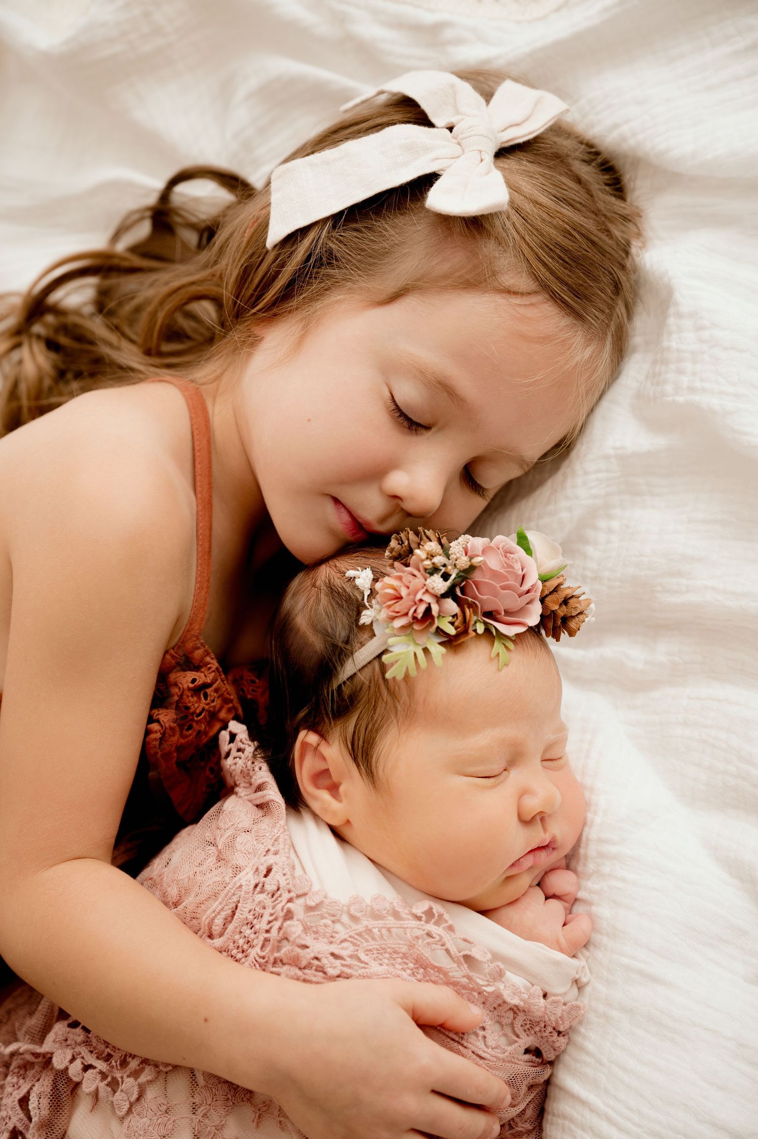 Sweet portrait of children in soft pink tones with floral crown and delicate embrace.