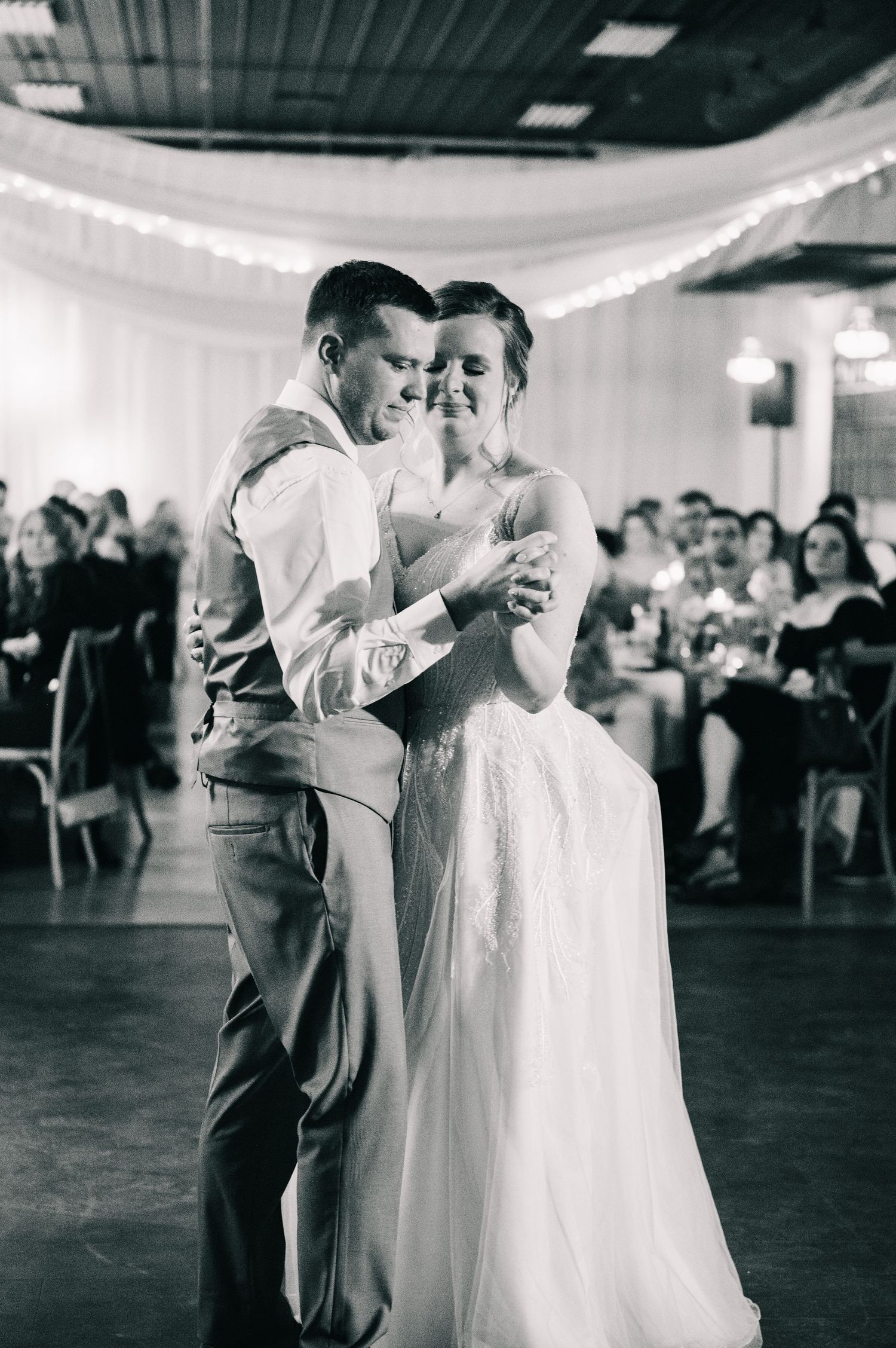 Black and white photo of bride and groom sharing first dance at wedding reception.