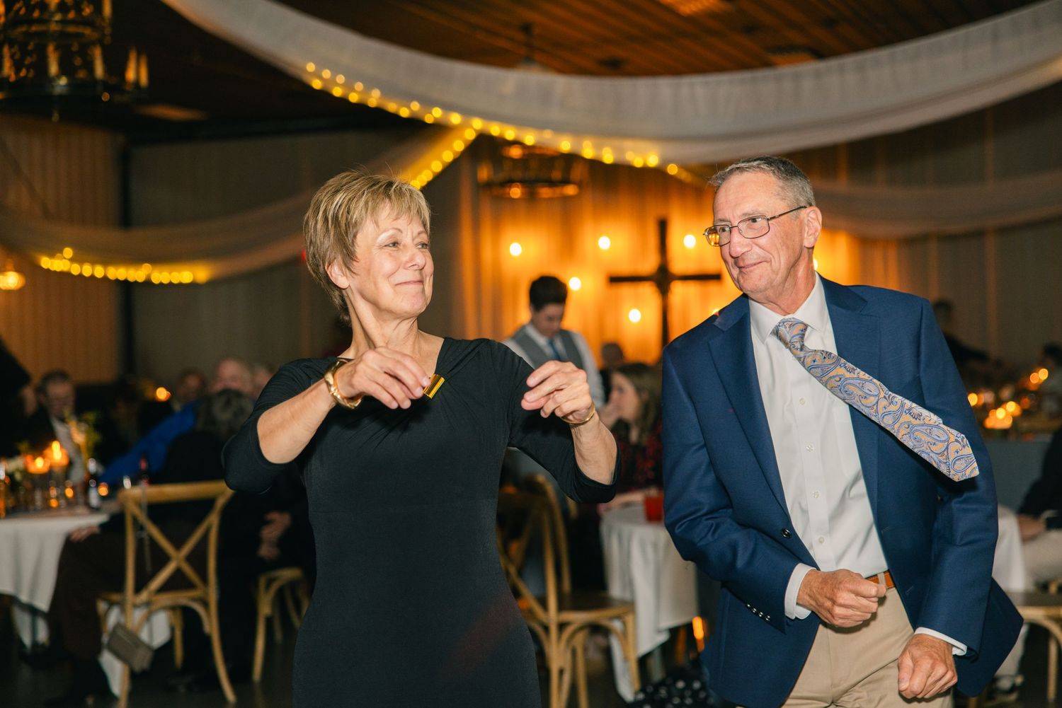 Older couple dancing and laughing together at an elegant wedding reception.