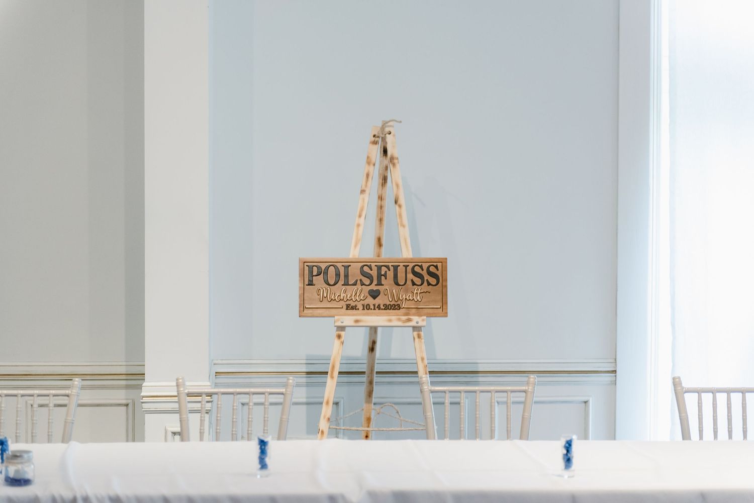 Central MN Wedding Photos | Wooden wedding welcome sign on easel reading Polspuss in elegant reception hall.