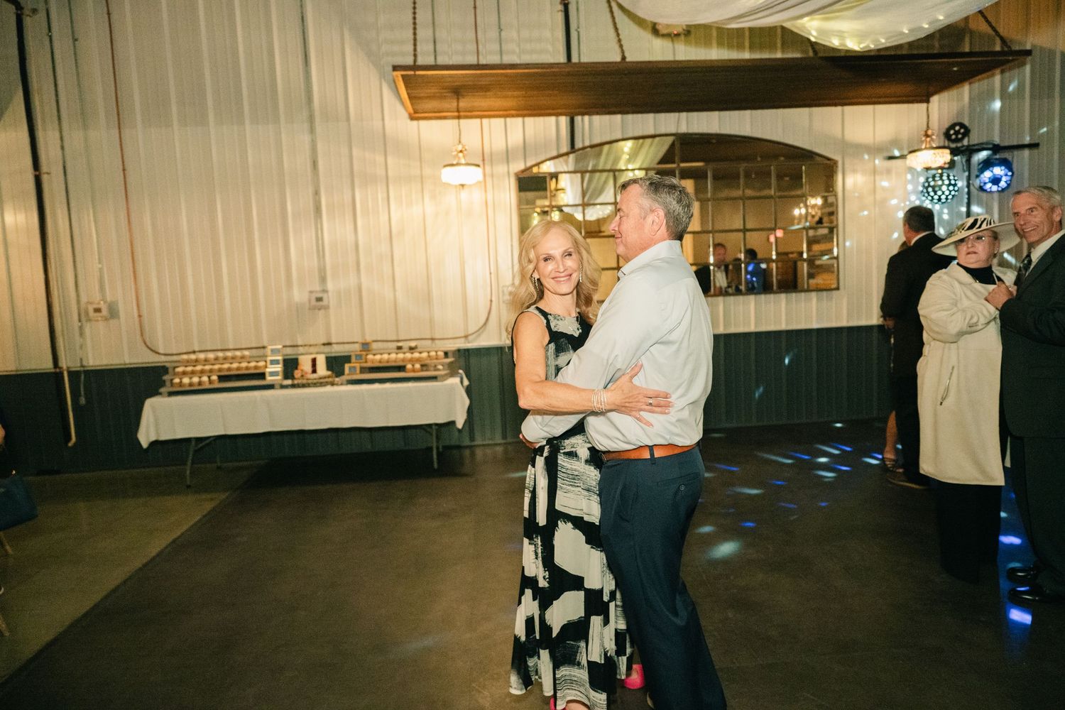 Couple shares slow dance on wedding reception dance floor in elegant white draped venue.