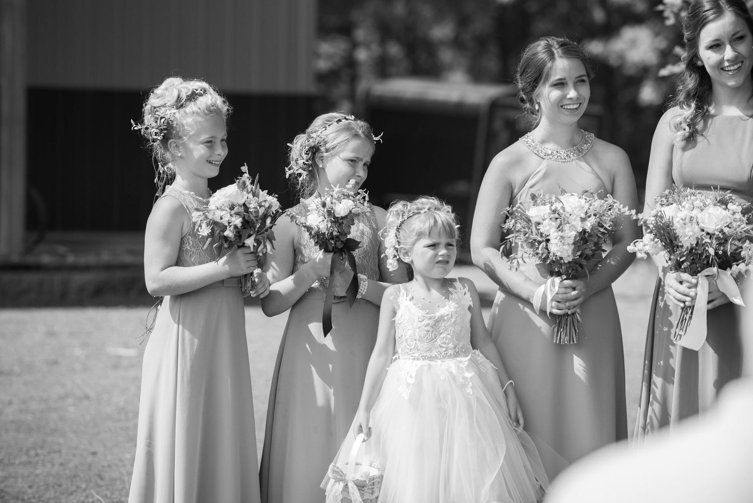 Black and white photo of bridesmaids in matching gowns and a flower girl in white standing together with bouquets. Zimmerman MN Weddings