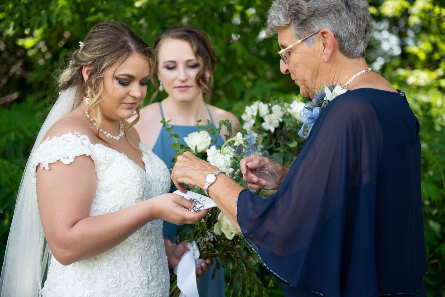 Wedding party poses together outdoors on a sunny day surrounded by lush greenery. Zimmerman MN Weddings