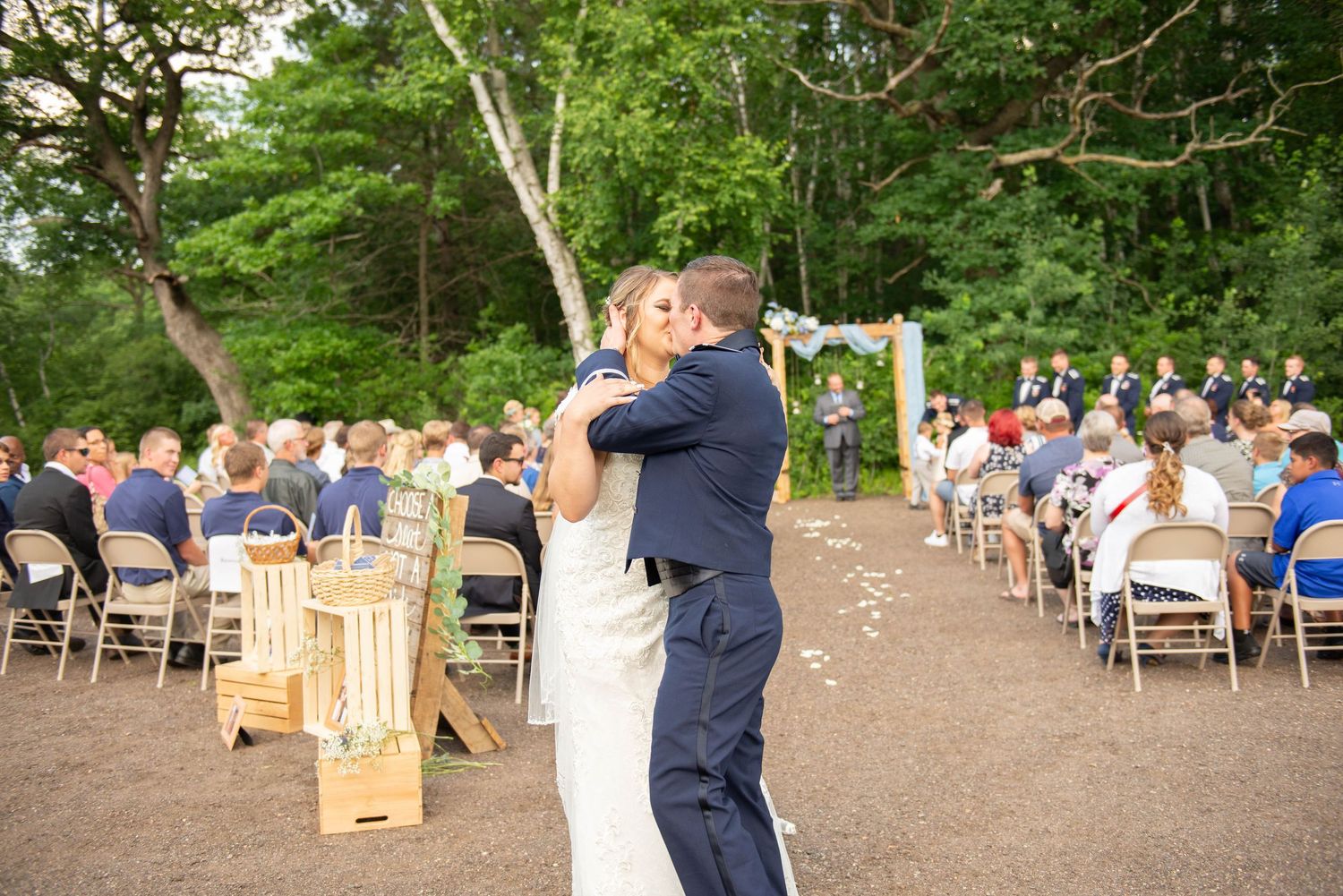 Couple dancing at an outdoor wedding reception surrounded by guests seated at tables in a wooded setting. Zimmerman MN Weddings