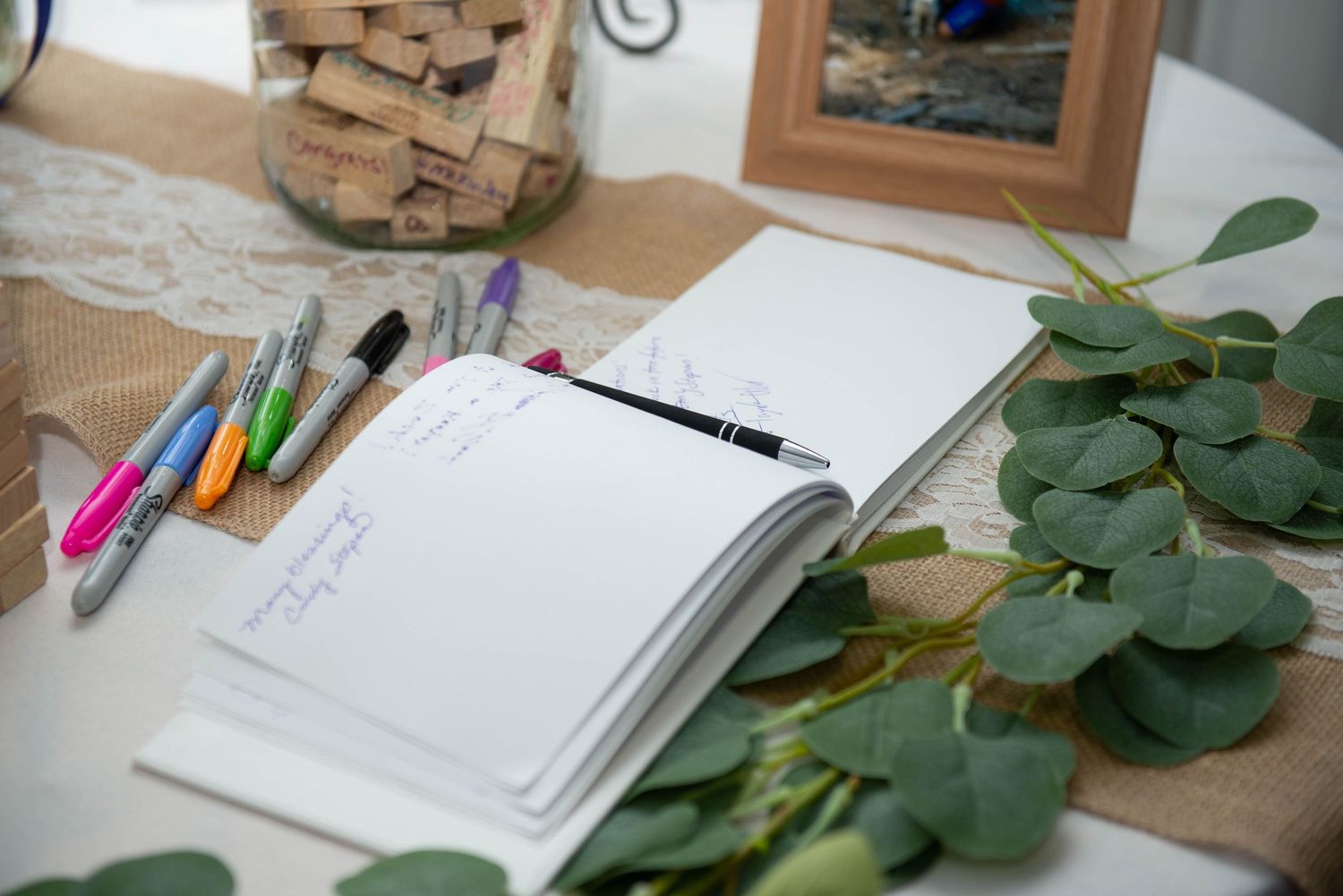 Rustic wedding decor layout with notebooks, eucalyptus leaves, and craft paper on wooden surface. Zimmerman MN Weddings