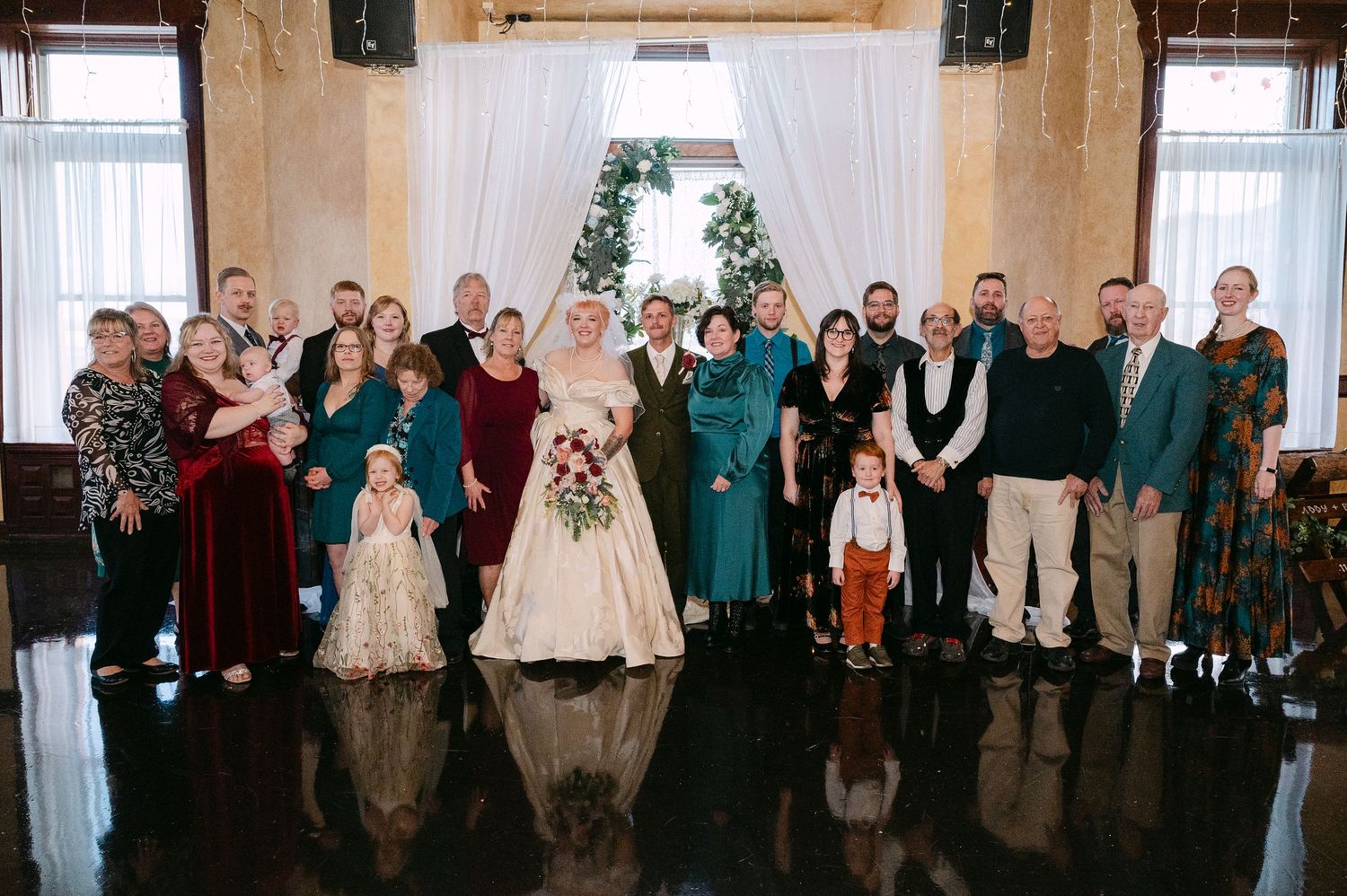 Central MN Wedding Photos | Large wedding party group photo in elegant venue with floral arch backdrop.