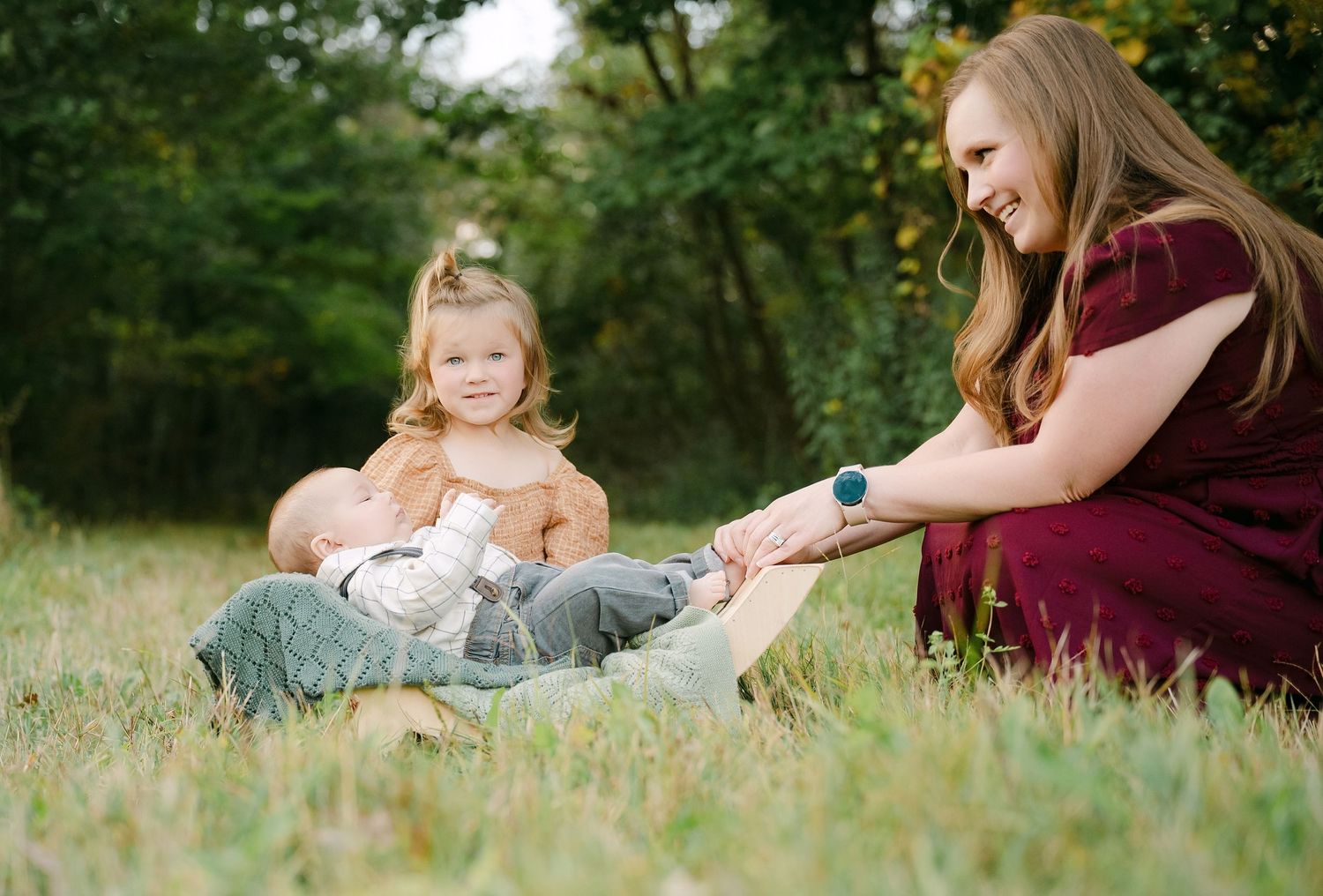 Mother and daughter sitting together in grass outdoors during a family photo session in natural lighting.. Minnesota milestone photographer