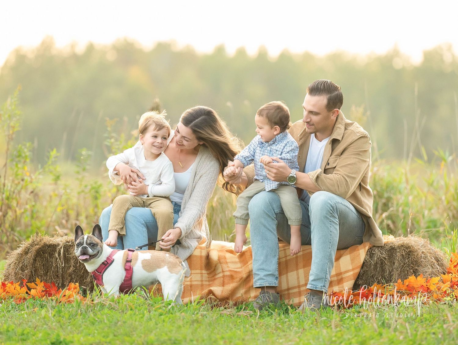 Family enjoying a playful moment together while laying in a vibrant autumn field during sunset.