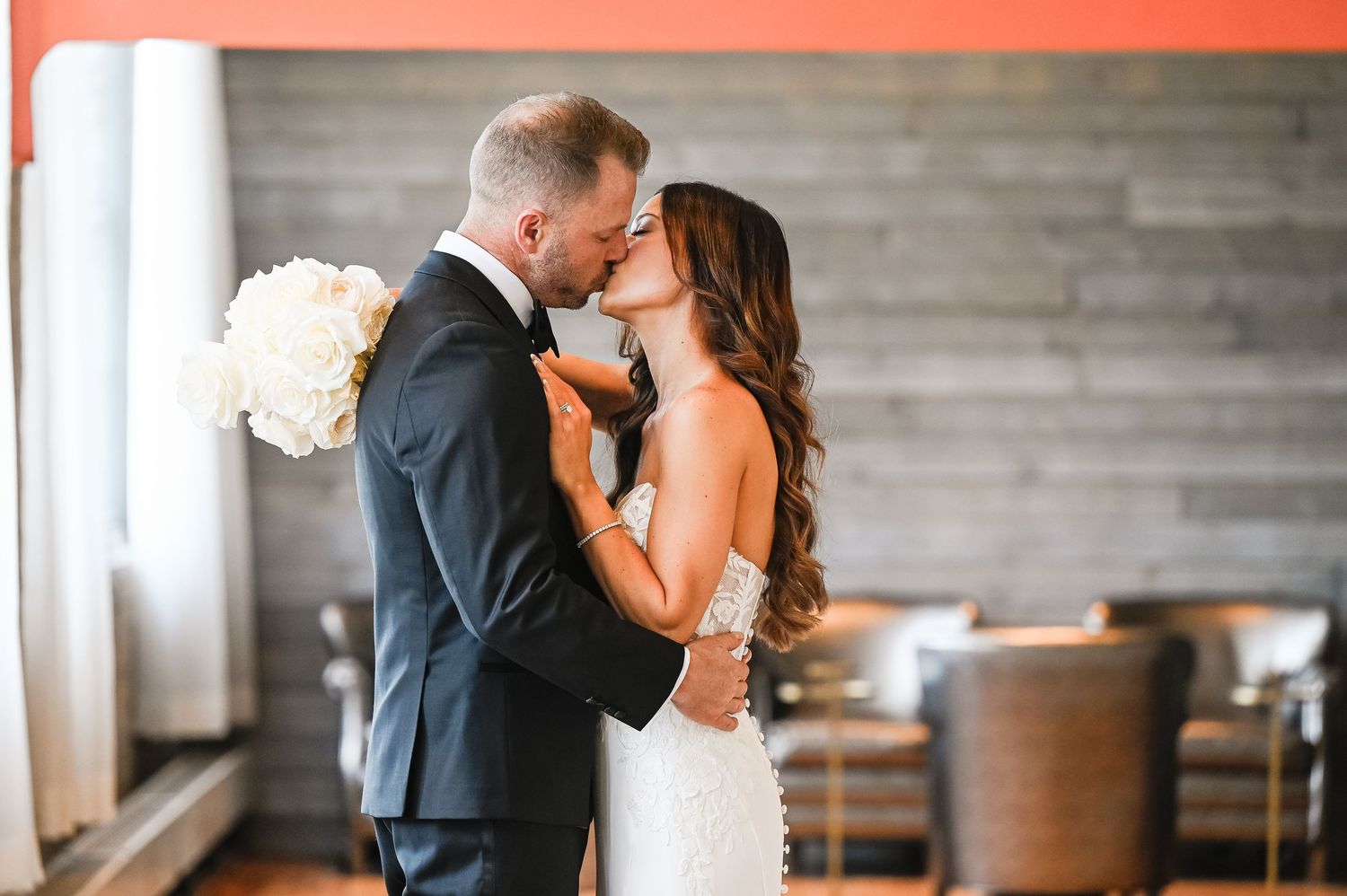 Romantic wedding portrait with couple sharing an intimate moment against white drapes.