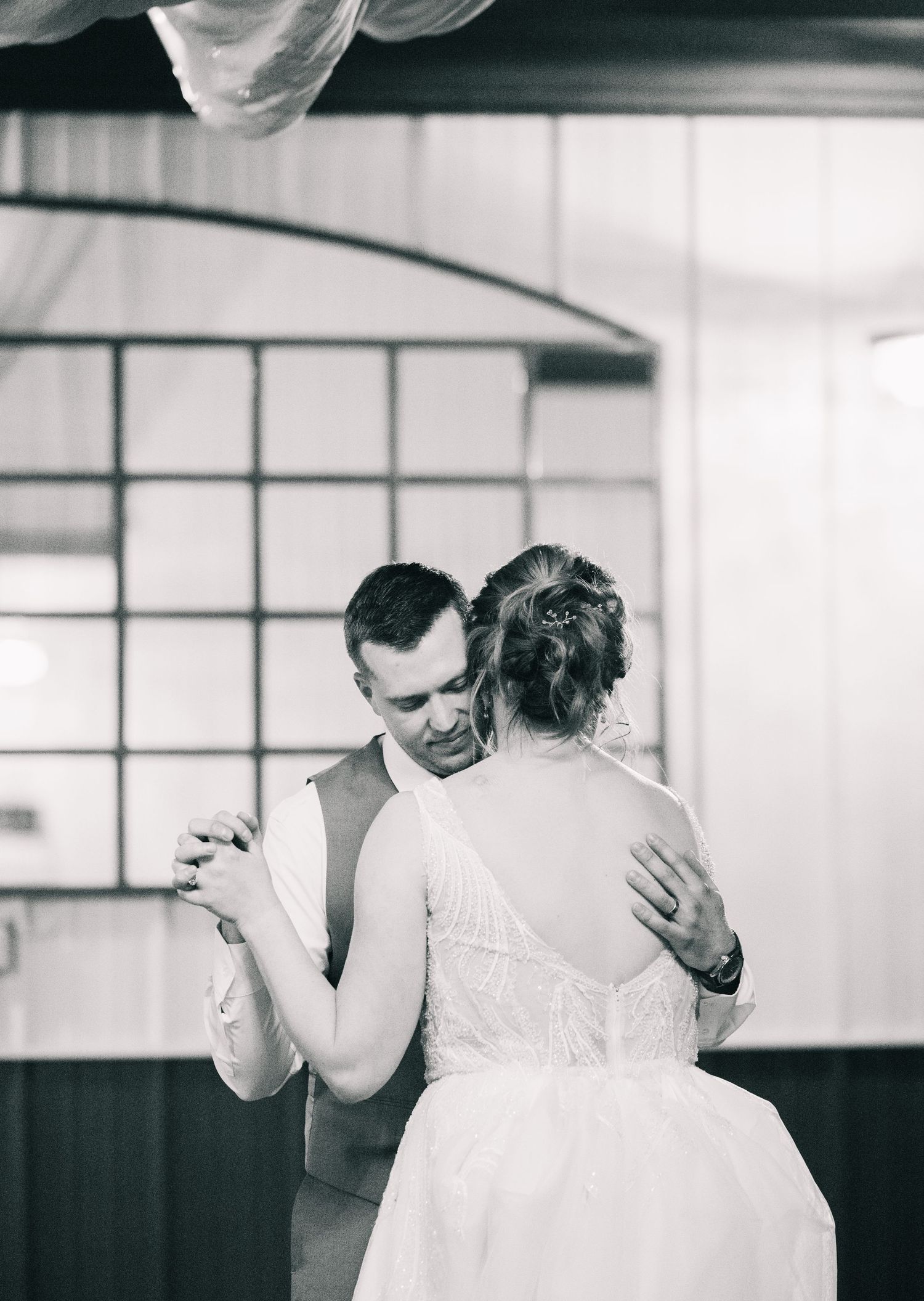 Black and white close-up of bride and groom sharing an intimate first dance at wedding.