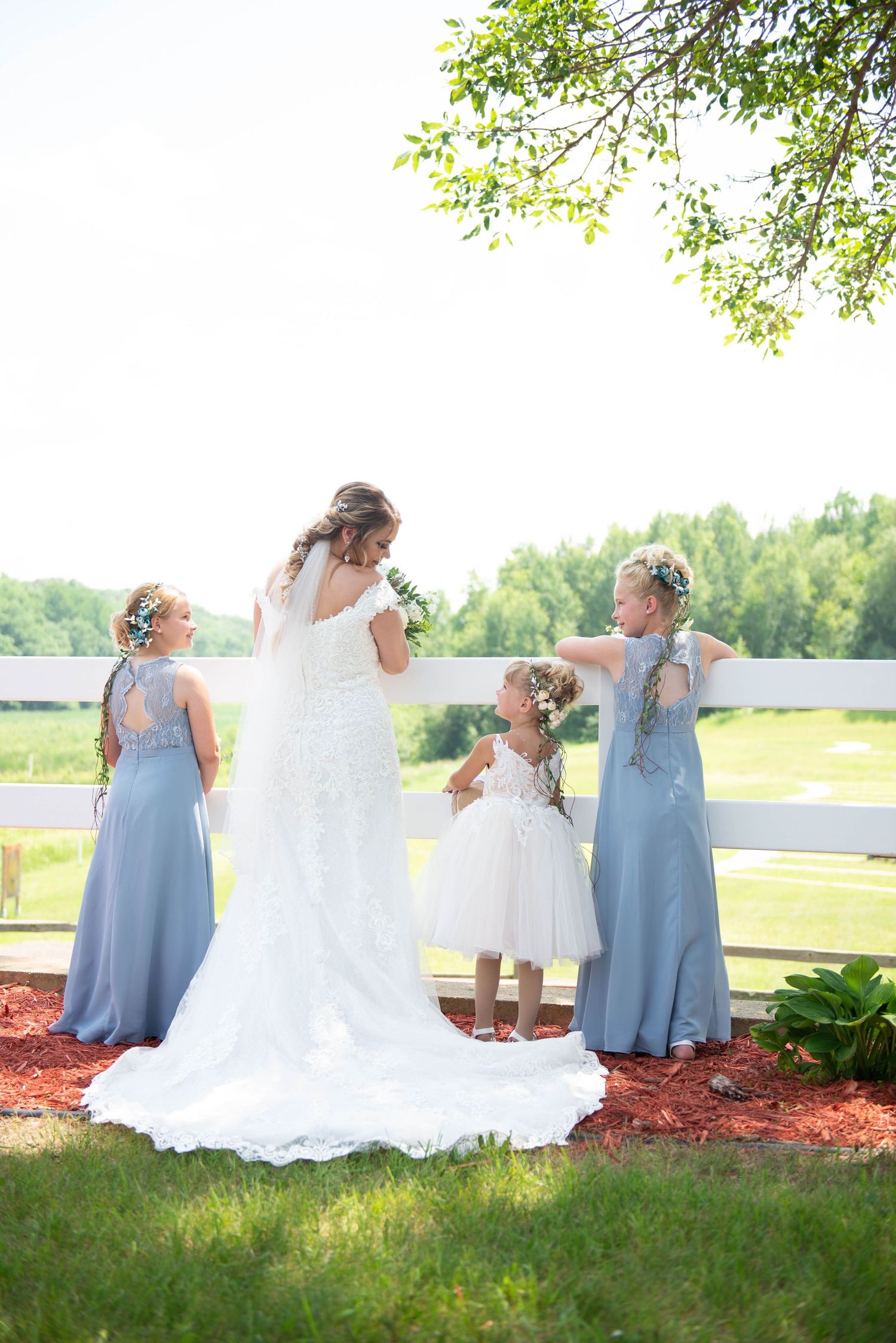 Wedding party in light blue dresses posing on green lawn with white flowers. Zimmerman MN Weddings