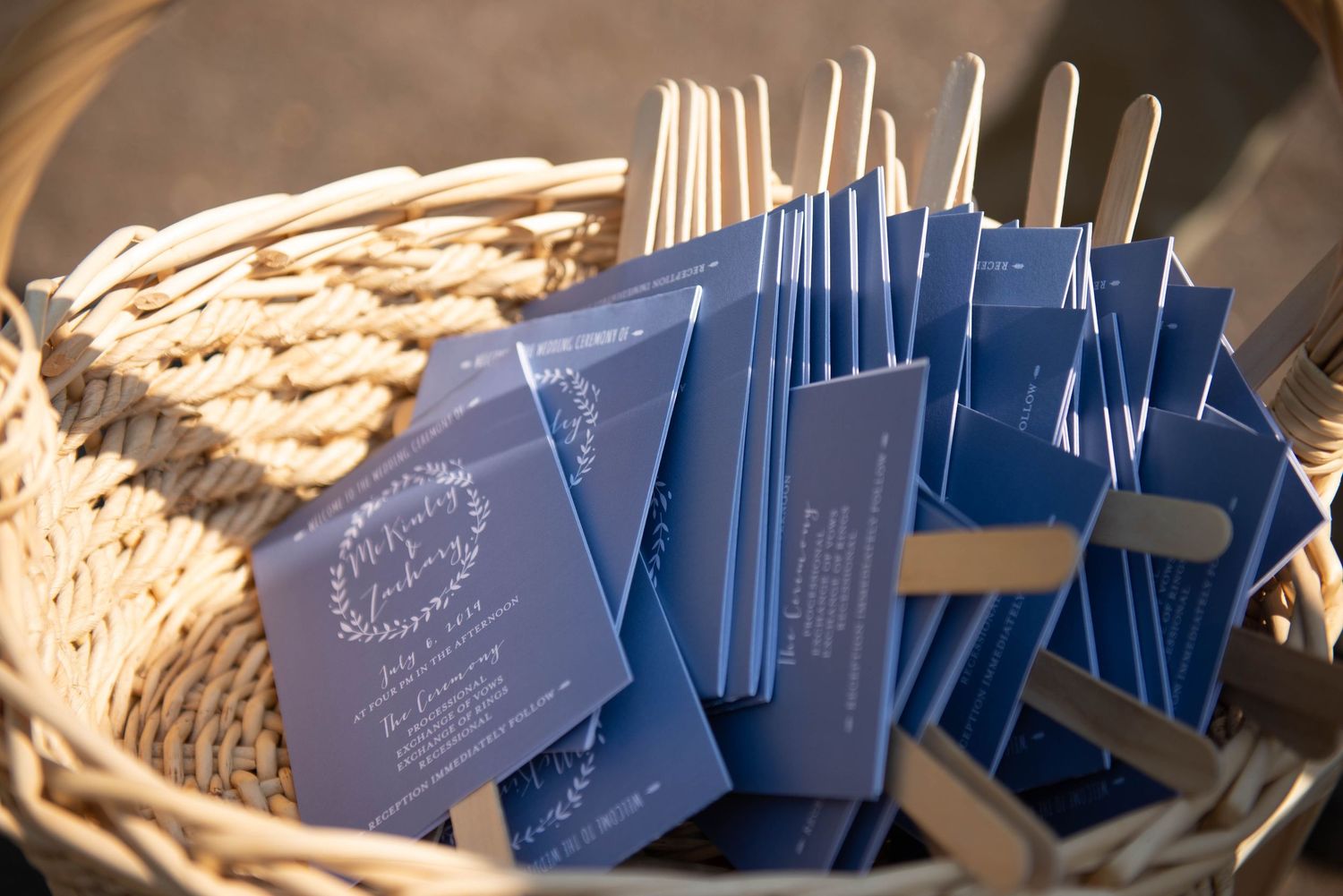 Navy blue wedding programs arranged in a woven basket. Zimmerman MN Weddings