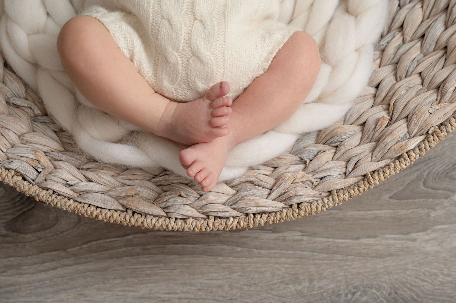 Minnesota Best newborn photographer - Tiny newborn baby feet resting in a cozy woven basket with soft neutral textured blanket.