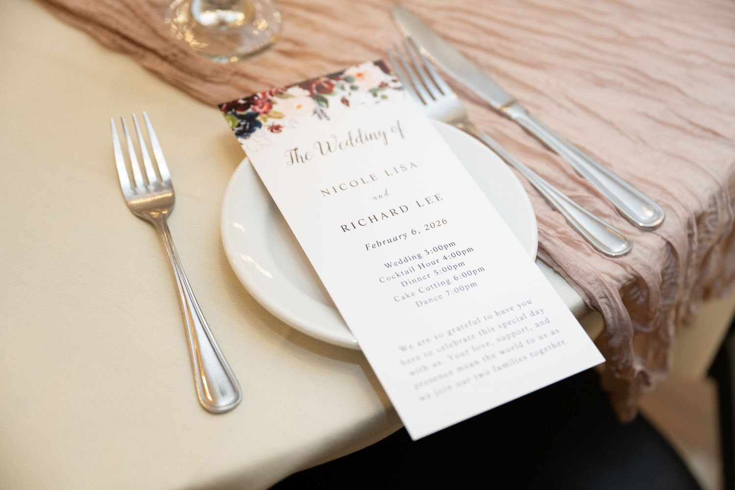 Place settings with white plates and silverware on a rustic wooden table with elegant menu cards.