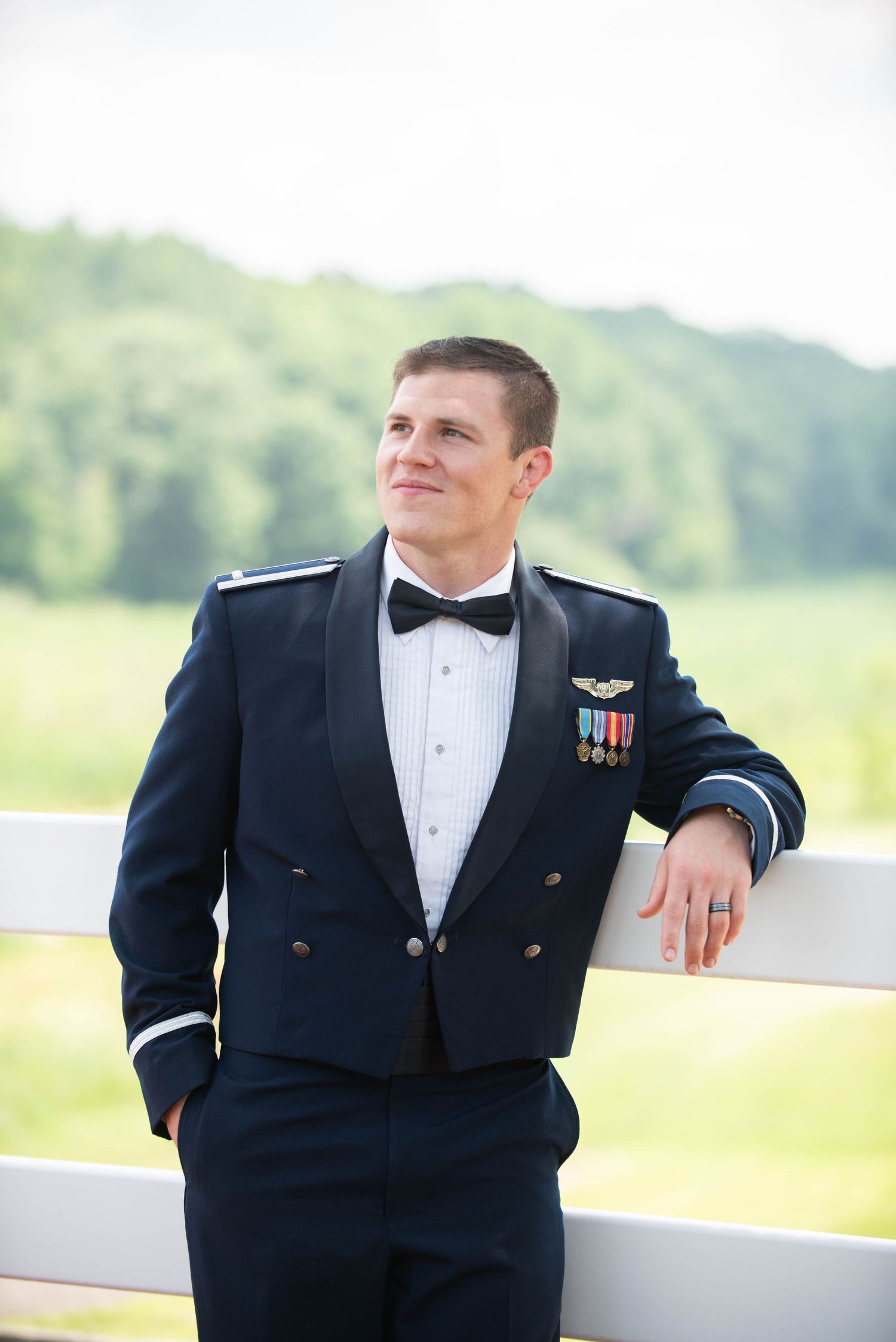 Military service member in formal dress uniform poses outdoors against white fence. Zimmerman MN Weddings
