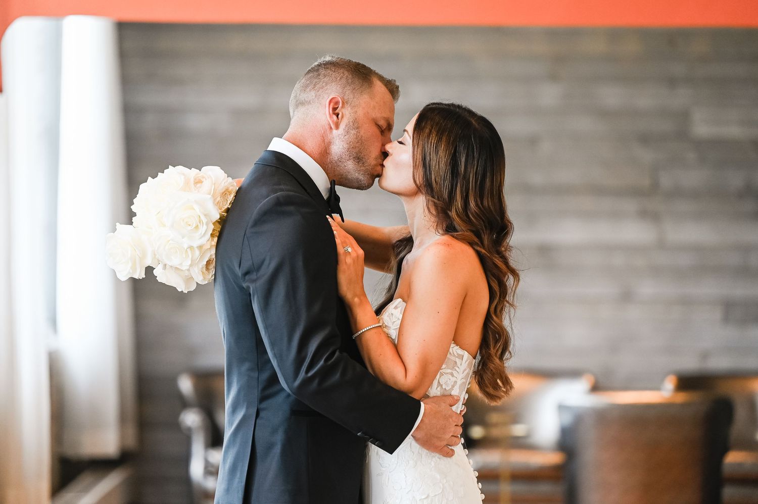 Couple shares romantic first look moment in front of industrial brick wall.