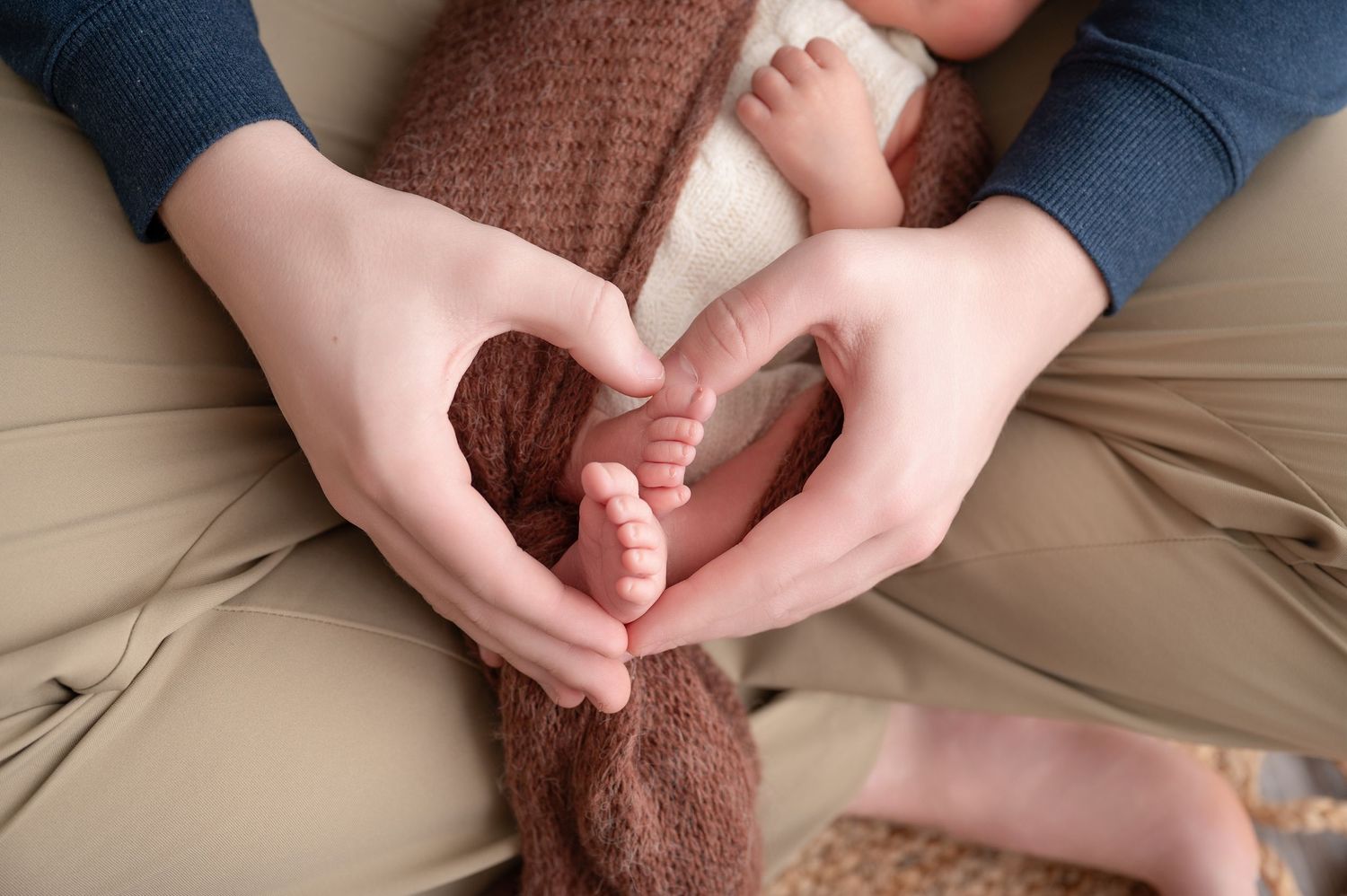 Minnesota Best newborn photographer - Close-up of hands framing newborn toes in a heart shape.