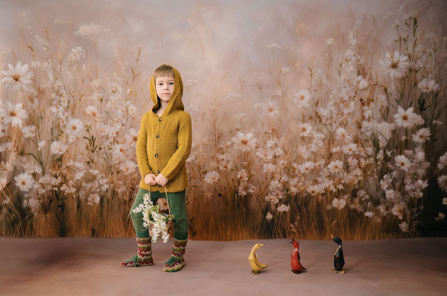 A figure in a yellow sweater poses against a rustic wall with whimsical flower blossoms creating a dreamy backdrop.