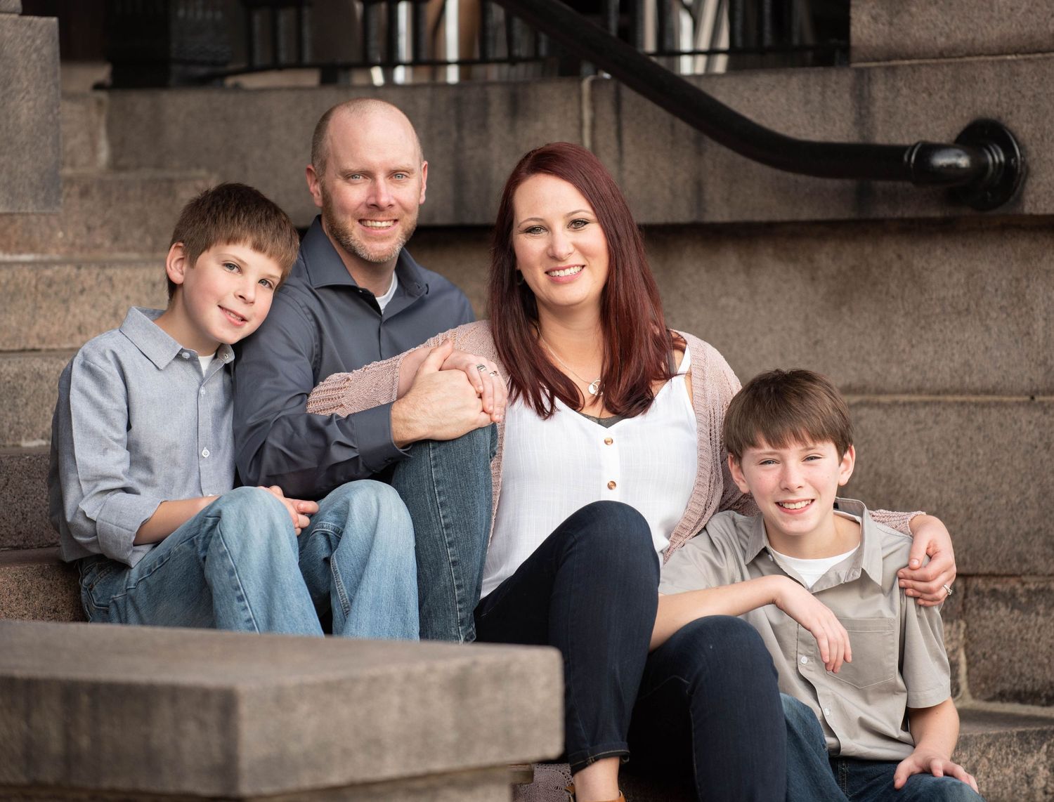 A family sits together on stone steps for a casual outdoor portrait session.