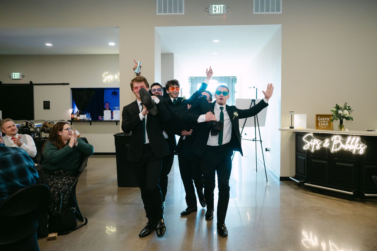 Wedding party members dancing together in a line formation during a reception celebration.
