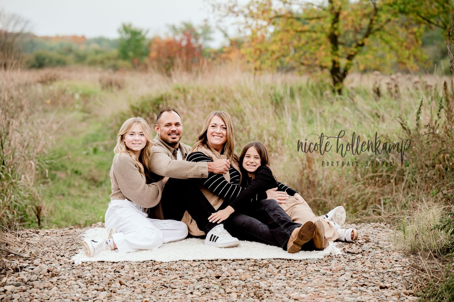 Candid family photo on blanket in autumn field.