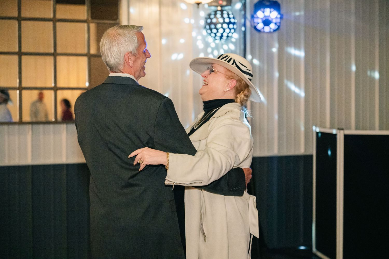 Elegant older couple shares a dance under disco lights at a wedding reception.