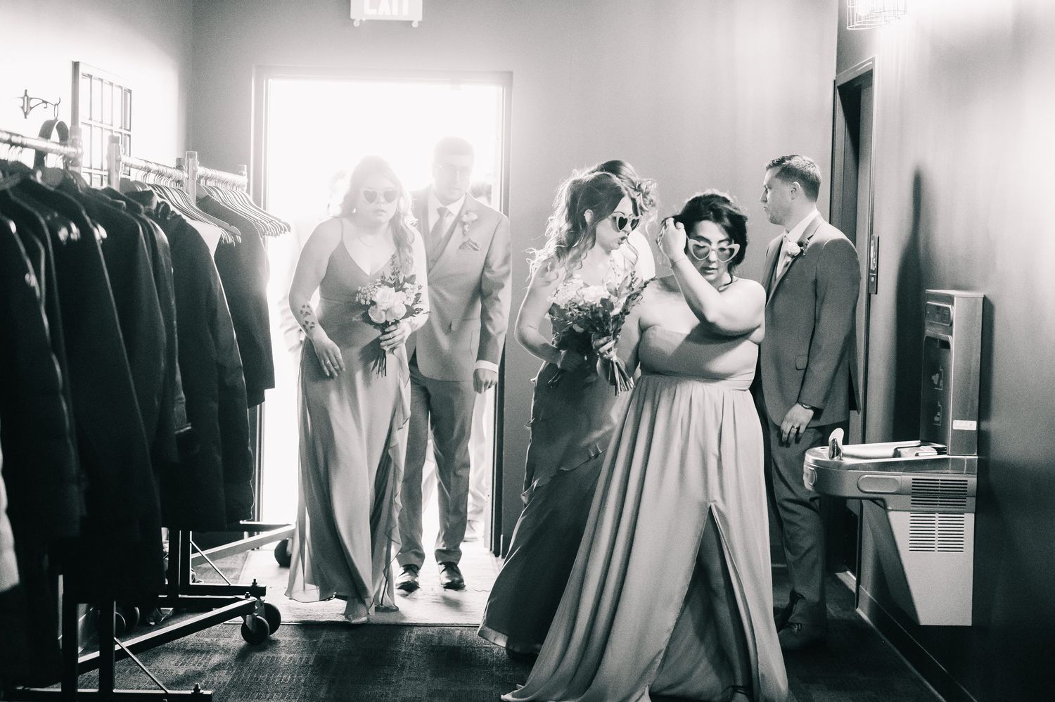 Black and white photo of bridesmaids helping bride prepare in a dressing room before the wedding ceremony.