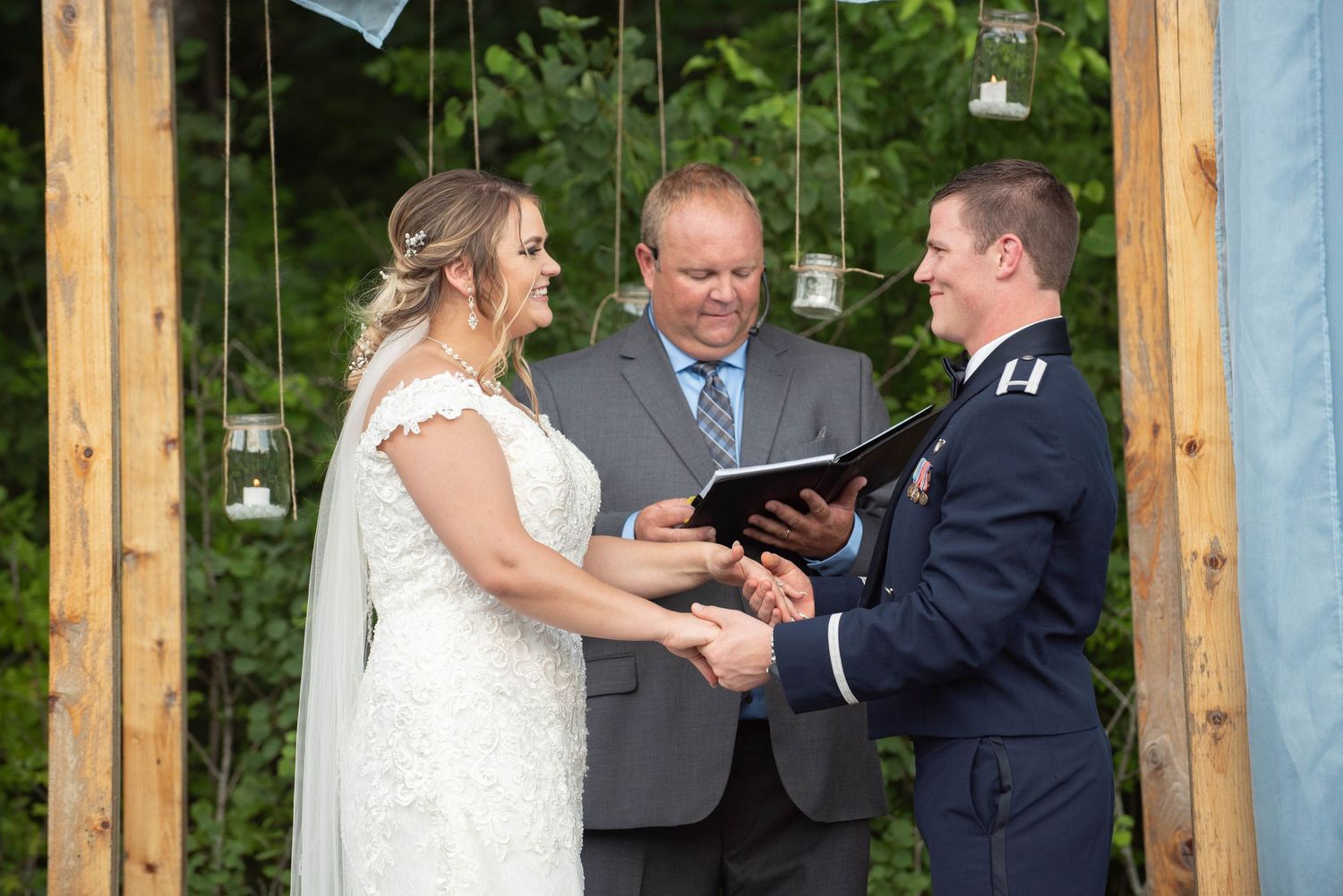 Intimate wedding ceremony moment under wooden arbor with forest scenery. Zimmerman MN Weddings