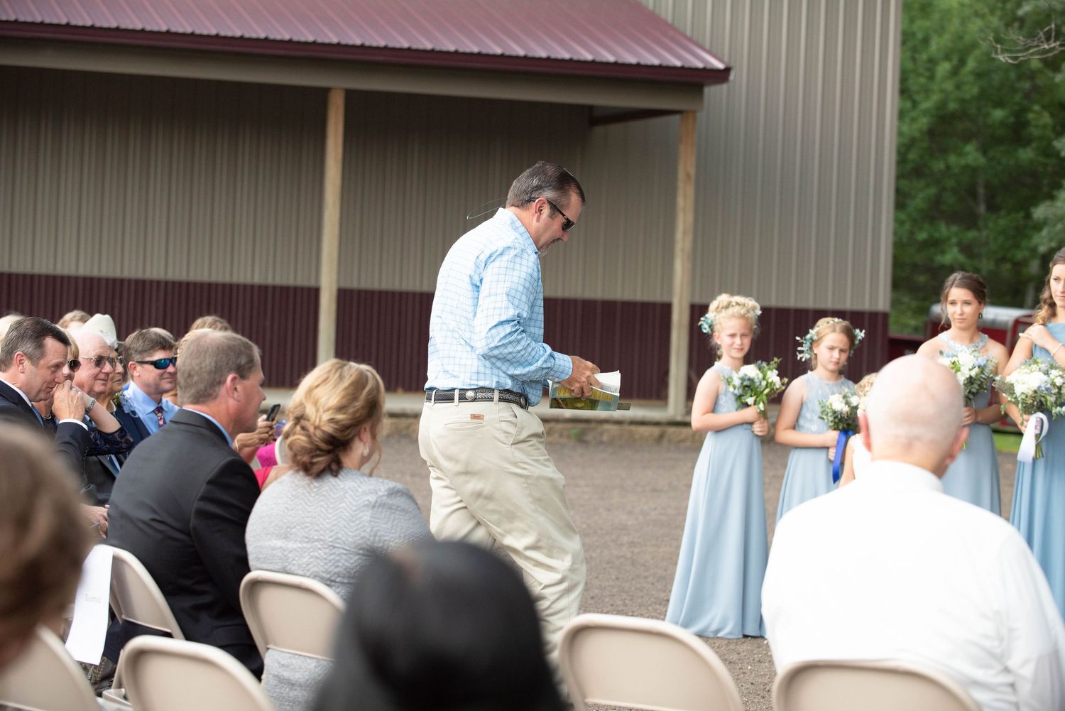 An outdoor pavilion with a red metal roof serves as backdrop for rows of white ceremony chairs. Zimmerman MN Weddings