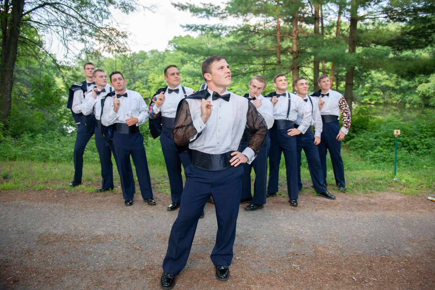 Groomsmen in navy suits and suspenders pose playfully for wedding party photo. Zimmerman MN Weddings
