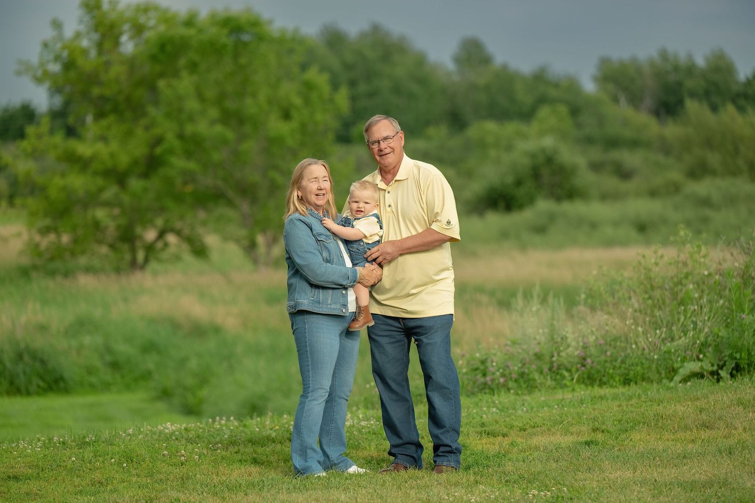 Green grassy field with dancing figures creating a casual outdoor portrait series at sunset. Family Portraits & Milestone Moments in Foresto