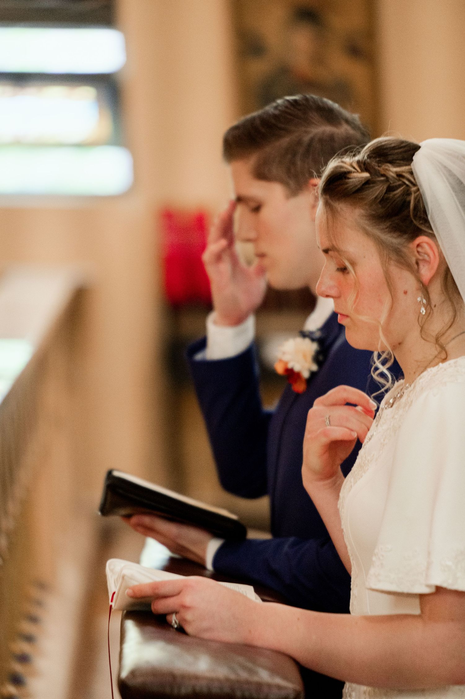 Wedding guests holding prayer books during an indoor church ceremony service.