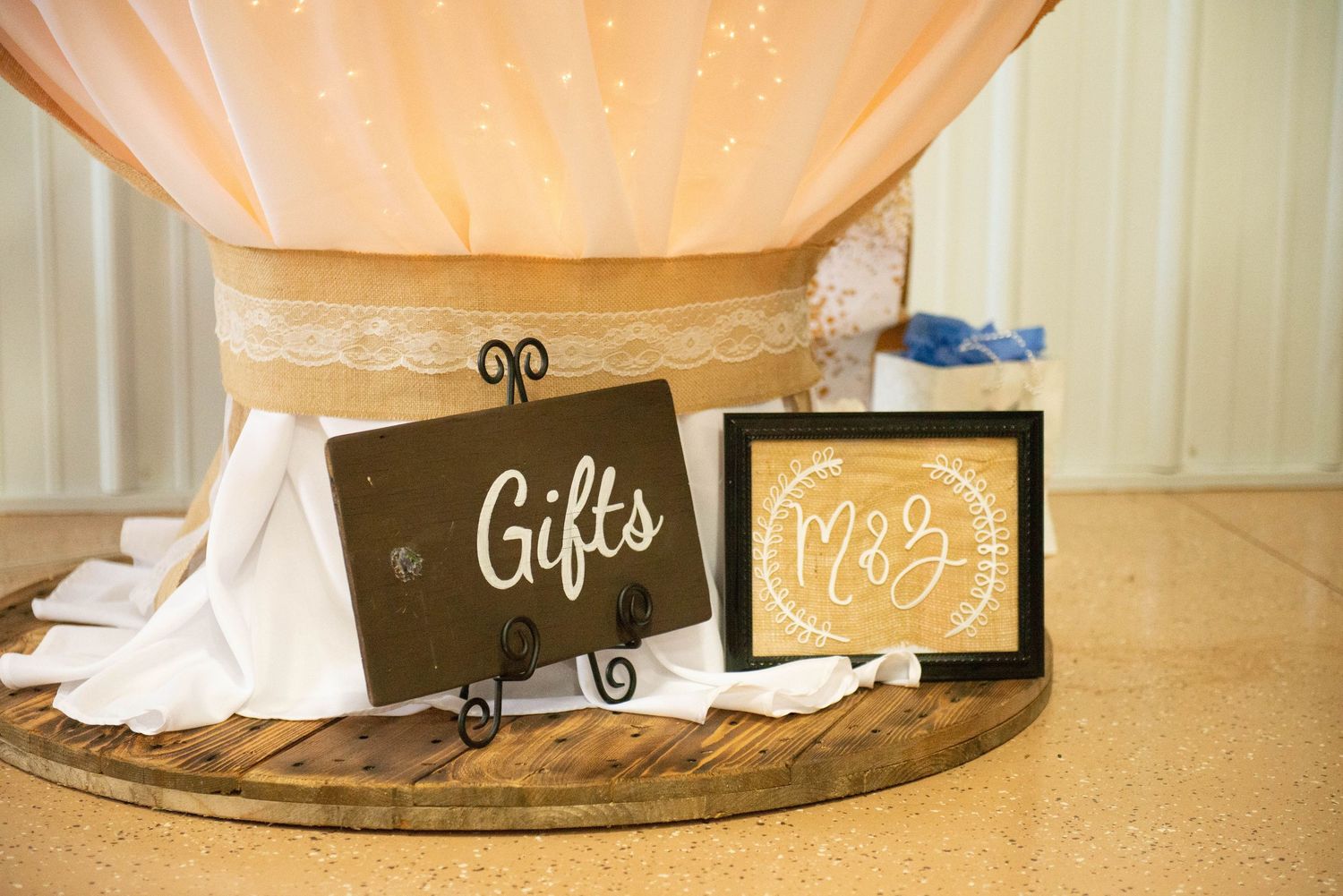 Two decorative gift signs displayed on black easels with peach drapery and white fabric in the background. Zimmerman MN Weddings