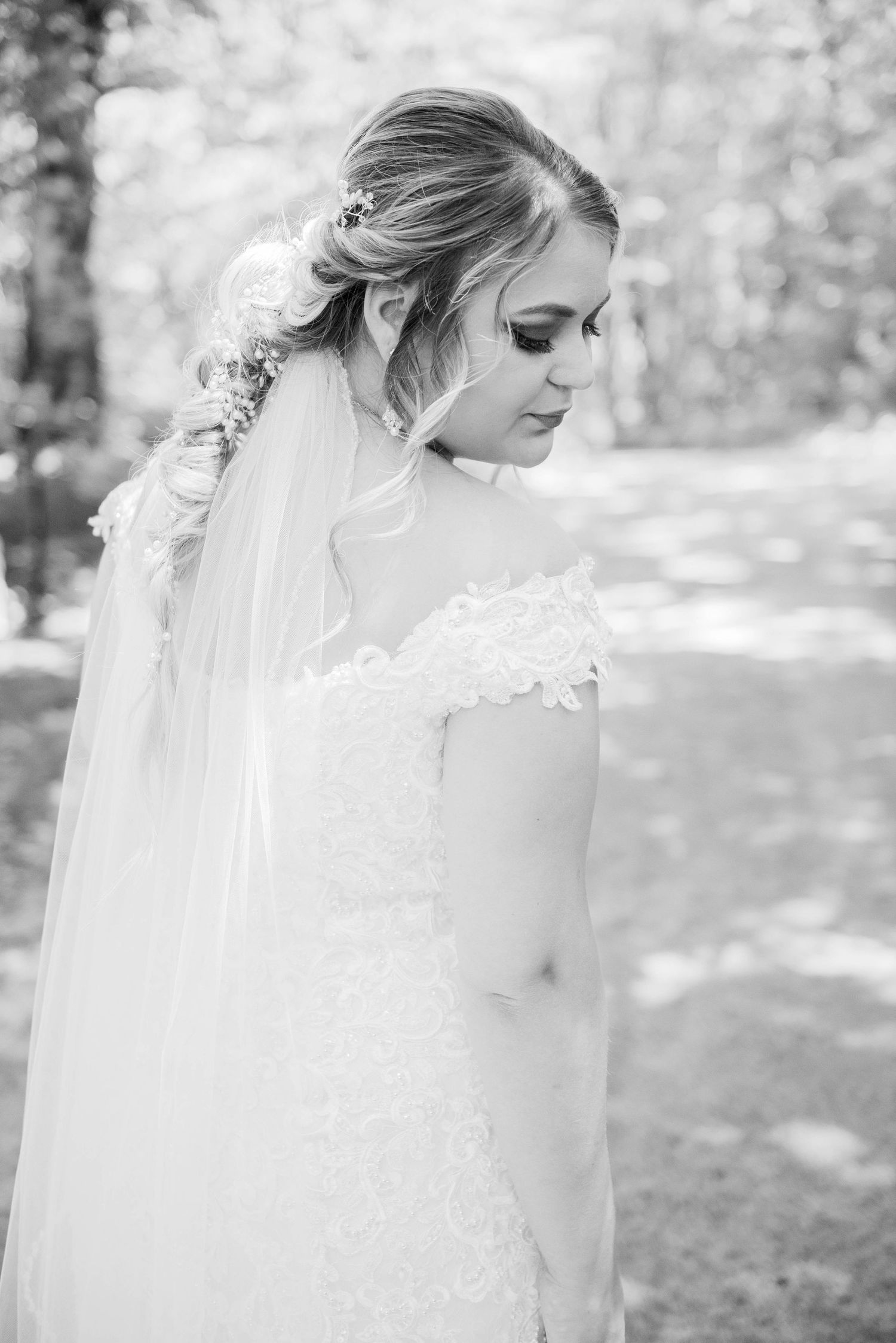 A black and white portrait of a bride with delicate lace details and a flowing veil in natural outdoor lighting. Zimmerman MN Weddings