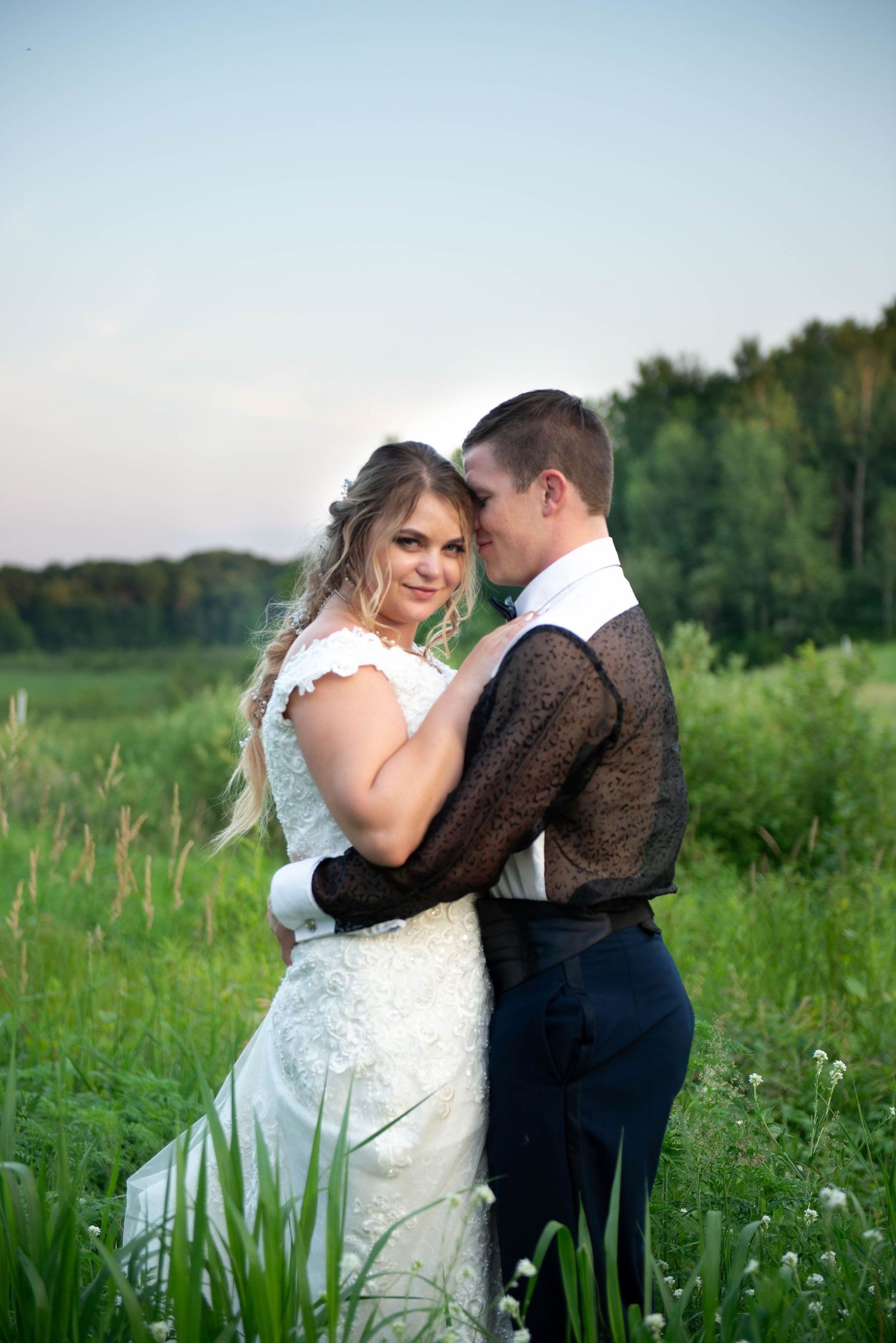 Wedding couple shares intimate moments while dancing in a lush green meadow at golden hour. Zimmerman MN Weddings