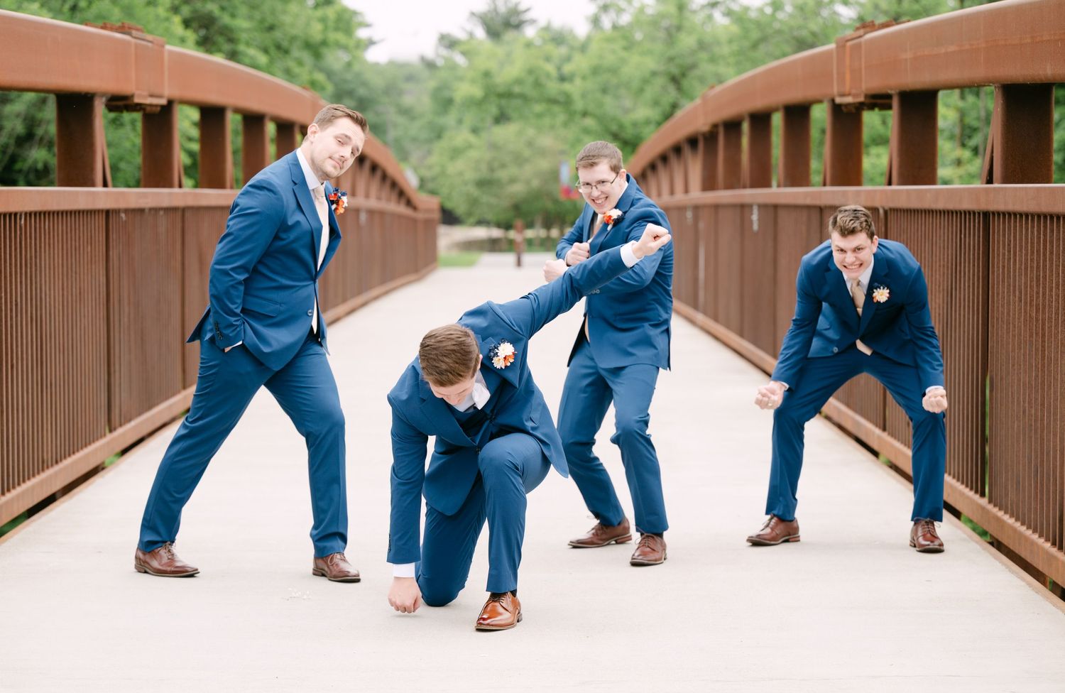 Fun wedding party photo sequence showing groomsmen falling down on wooden bridge.