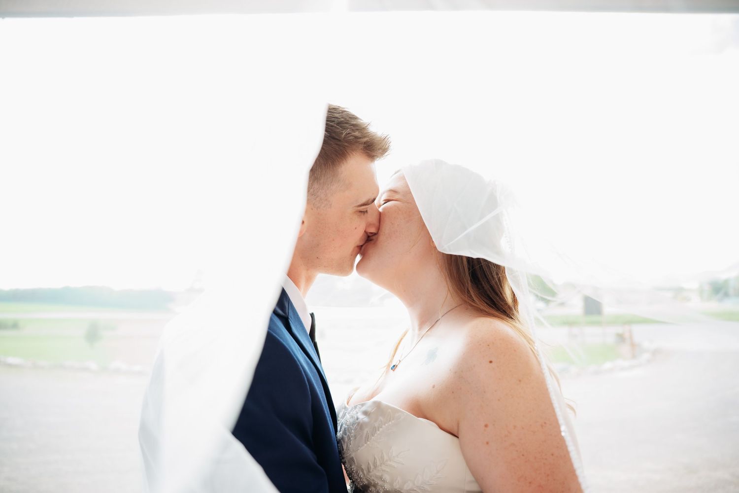 A couple embraces during their outdoor wedding ceremony with scenic countryside views in the background. Pease Minnesota Wedding at Northern