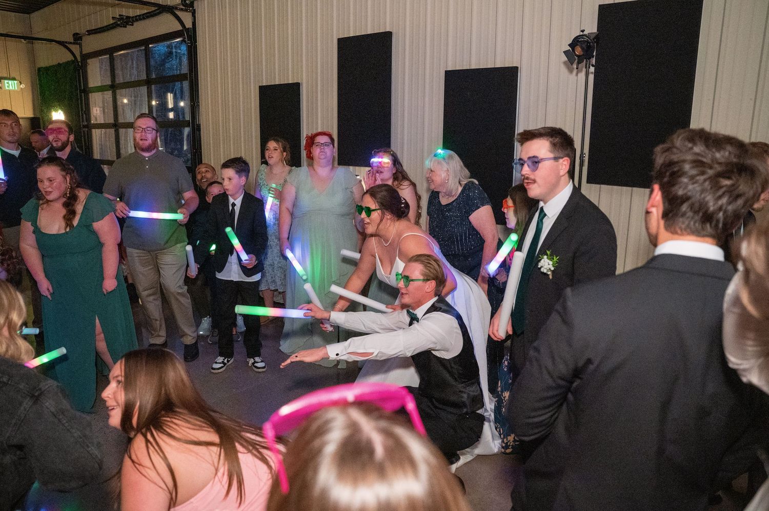 Wedding reception dance party with guests holding colorful light sticks.
