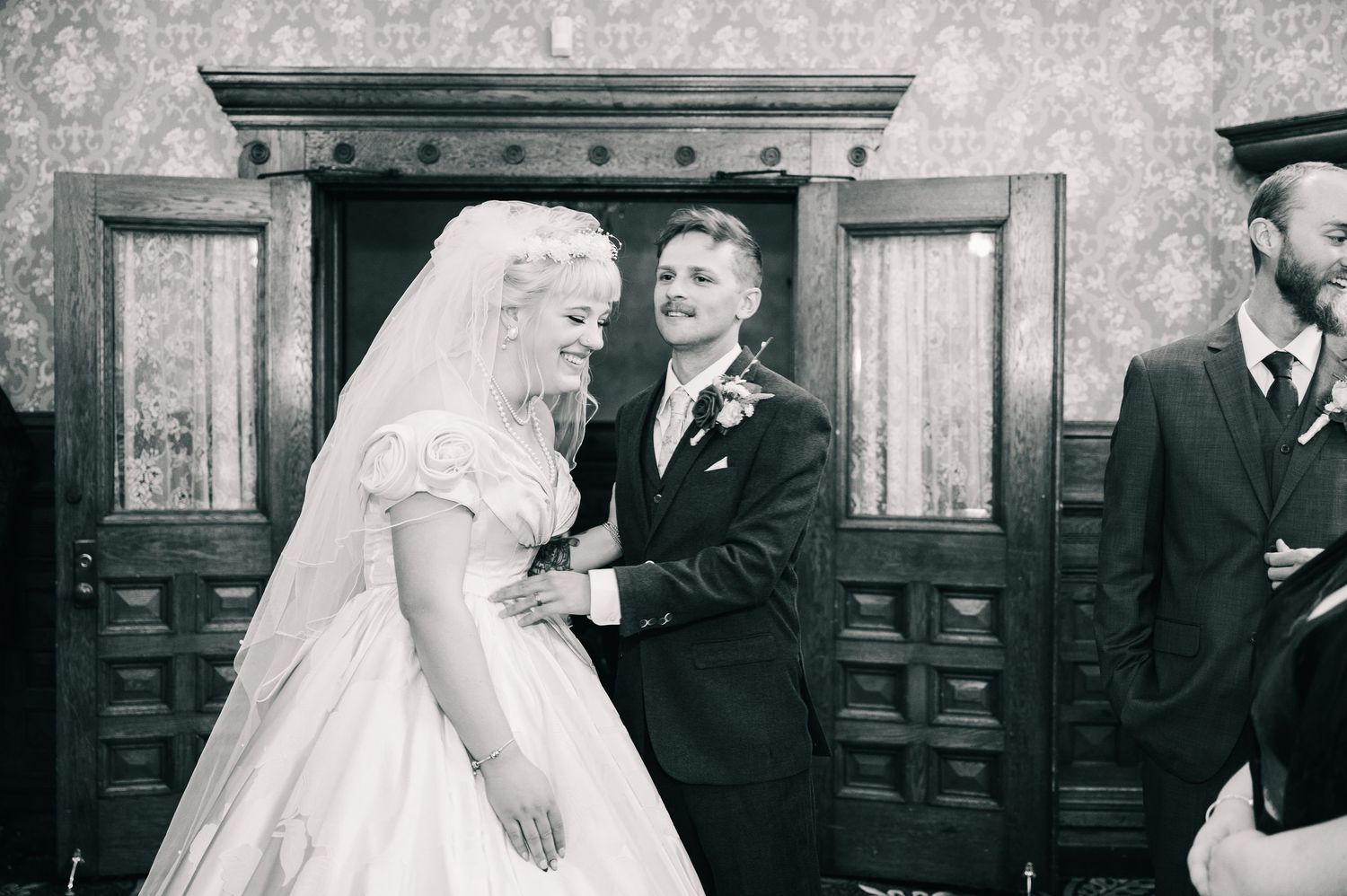 Central MN Wedding Photos | Black and white photo of bride and groom sharing a joyful moment at their wedding ceremony.