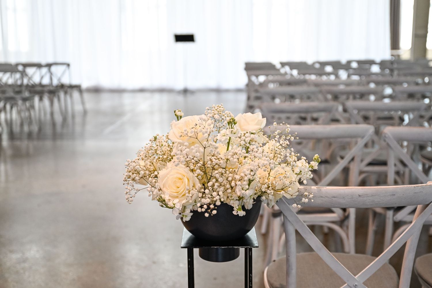 White floral arrangements with baby's breath decorating wedding venue seating area.