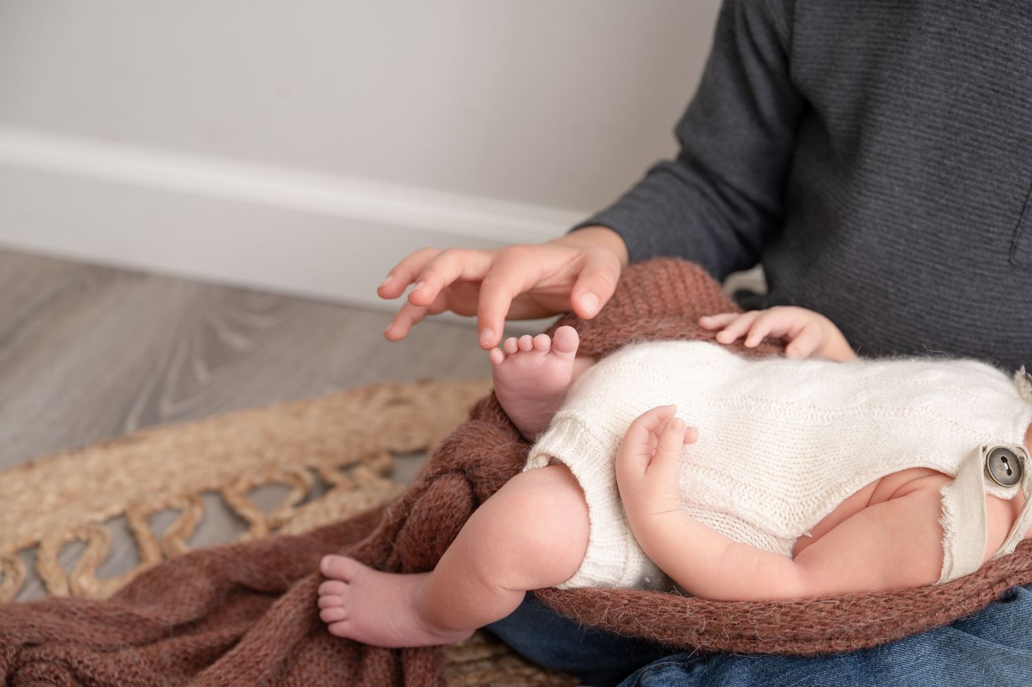 Minnesota Best newborn photographer - Sibling hands delicately touching newborn toes.