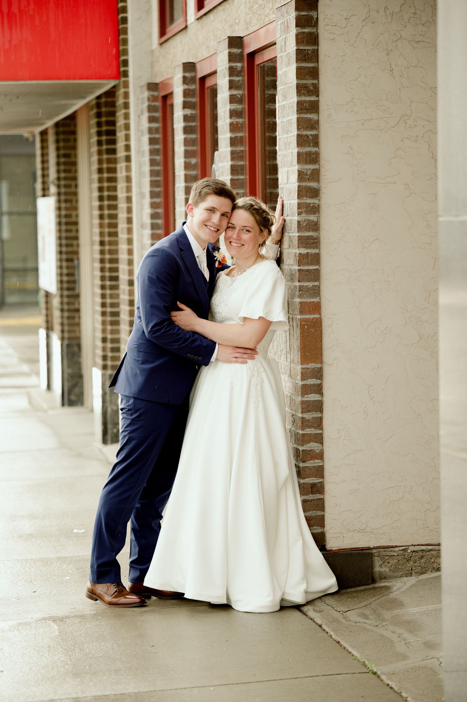 Wedding couple shares romantic kisses in a series of connected photos under a brick colonnade walkway.