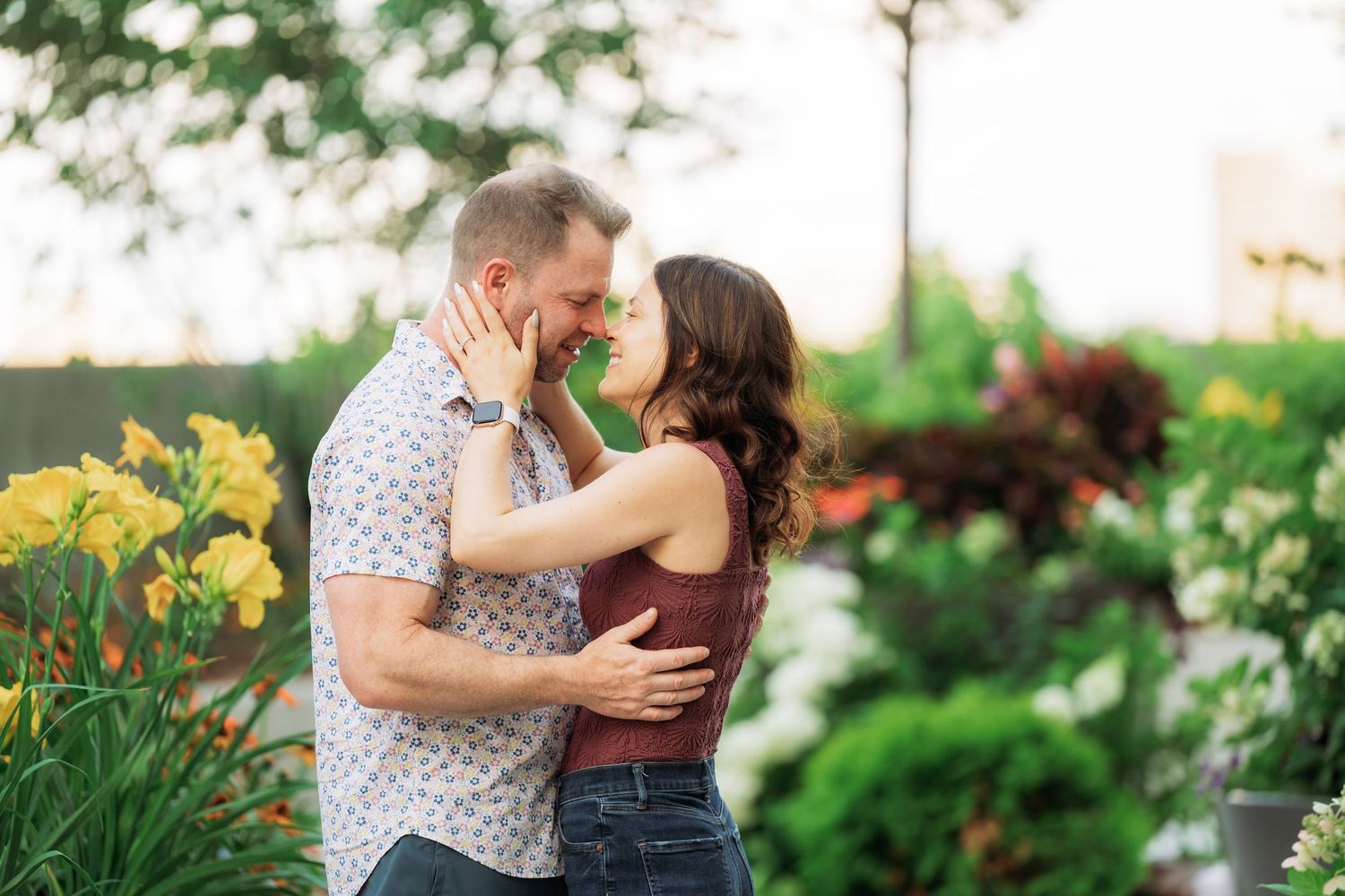 A romantic couple sharing tender moments together in a blooming garden with yellow daylilies on display.