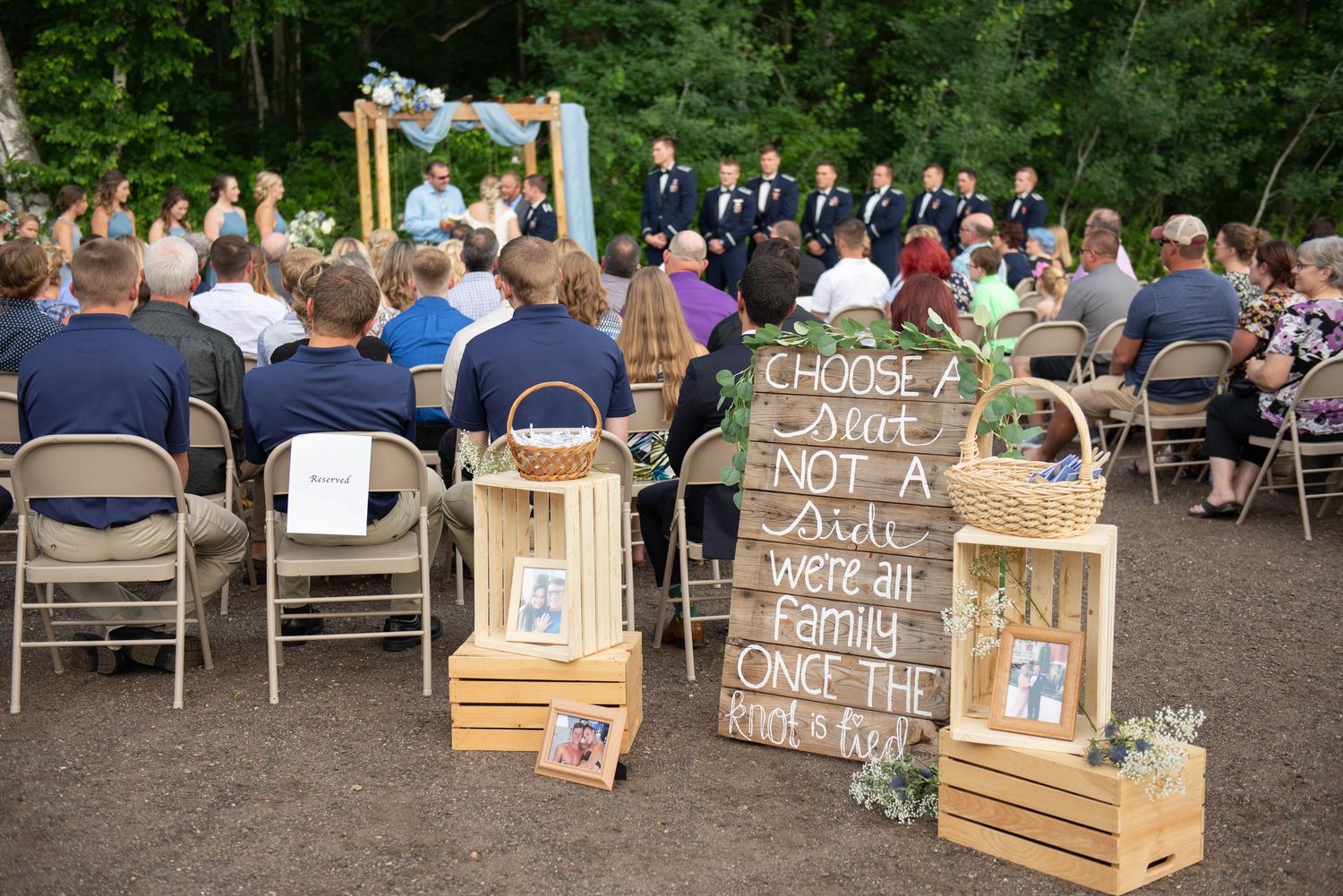 Outdoor wedding reception setup with wooden crates and rustic signage at tables arranged on a patio. Zimmerman MN Weddings