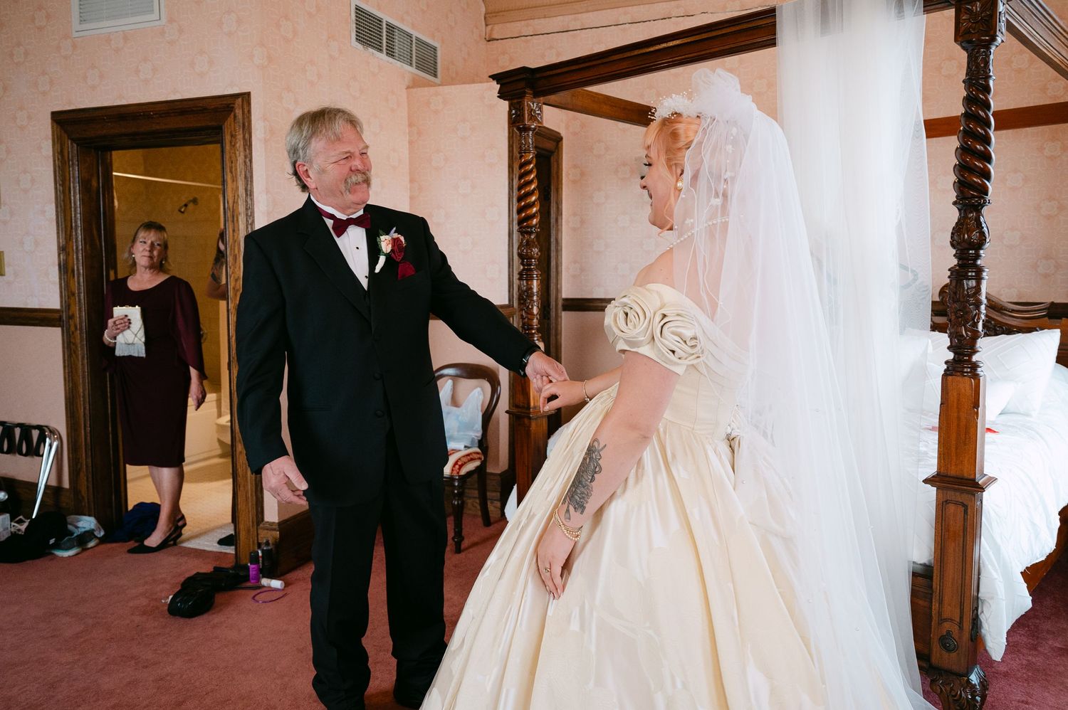 Central MN Wedding Photos | Father in tuxedo shares tender first look moment with bride in ivory ballgown and veil in elegant hotel room.