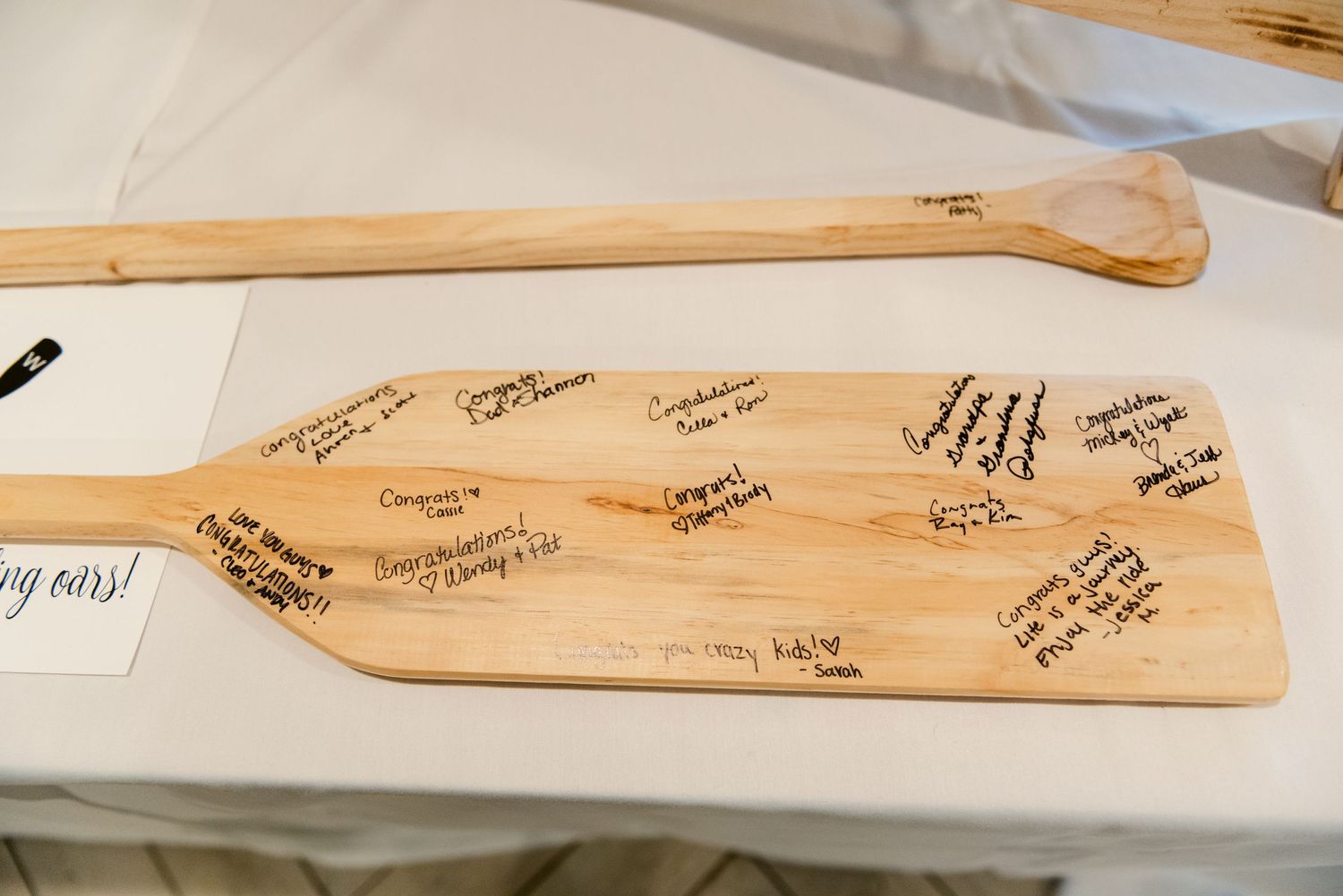 Central MN Wedding Photos | Wooden oar guest book signed with congratulatory messages at wedding reception.