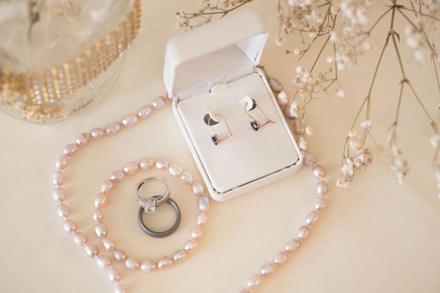 Delicate pearl necklaces and vintage jewelry arranged on cream lace fabric with soft lighting.